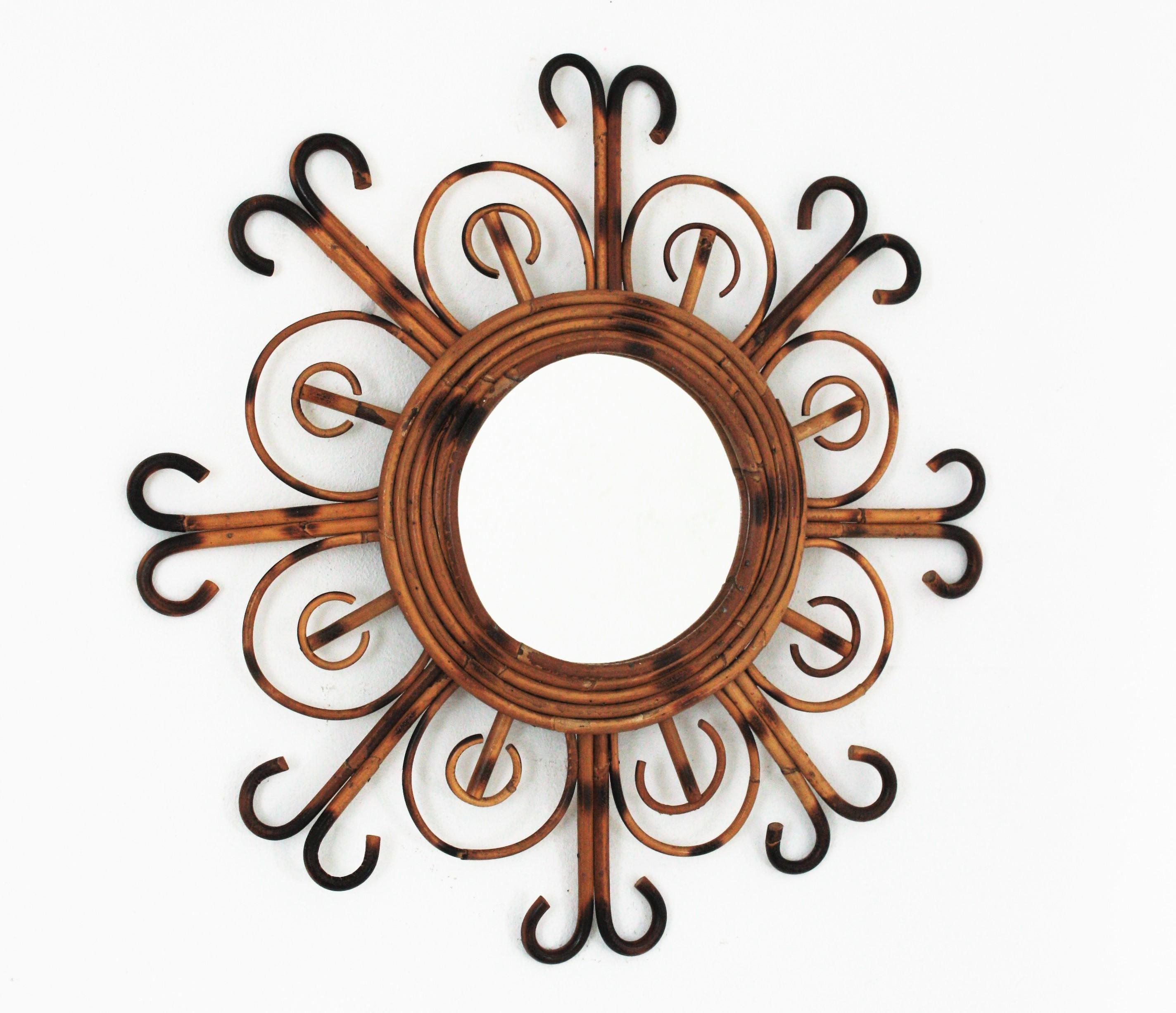 Auffälliger Spiegel in Form einer Blume / Sonnenschliff aus Rattan mit Pyrographie-Details. Hergestellt in Frankreich in den 1950er Jahren. 
Dieser Wandspiegel hat einen Rattanrahmen aus Rattanblättern, die sich mit geschwungenen Strahlen am Ende