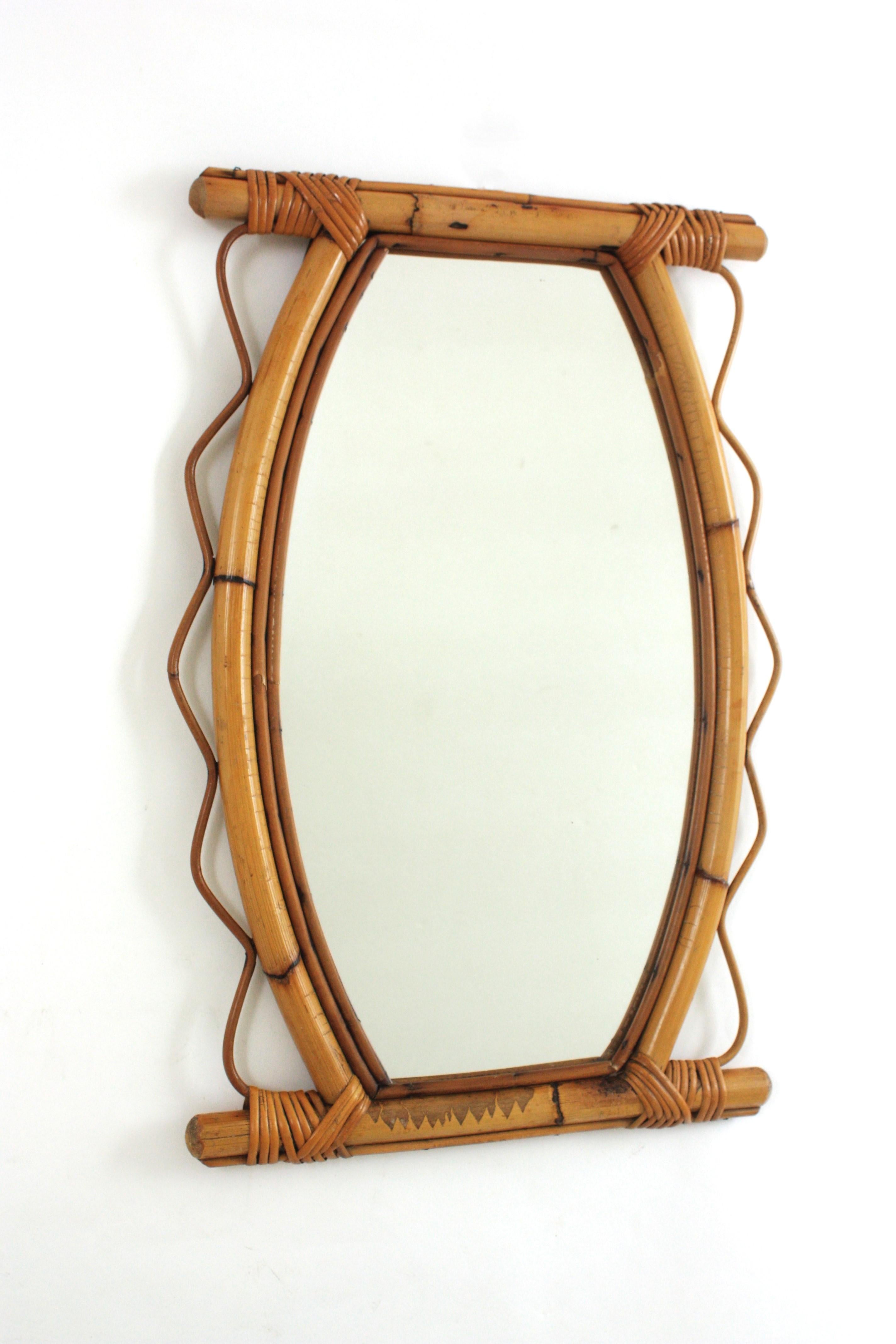 Eye-catching handcrafted bamboo and rattan mirror with scalloped detail surrounding the frame. France, 1950s-1960s.
This Mediterranean wall mirror features a bamboo / thick rattan frame surrounded by jagged rattan accents on both sides. 
This mirror