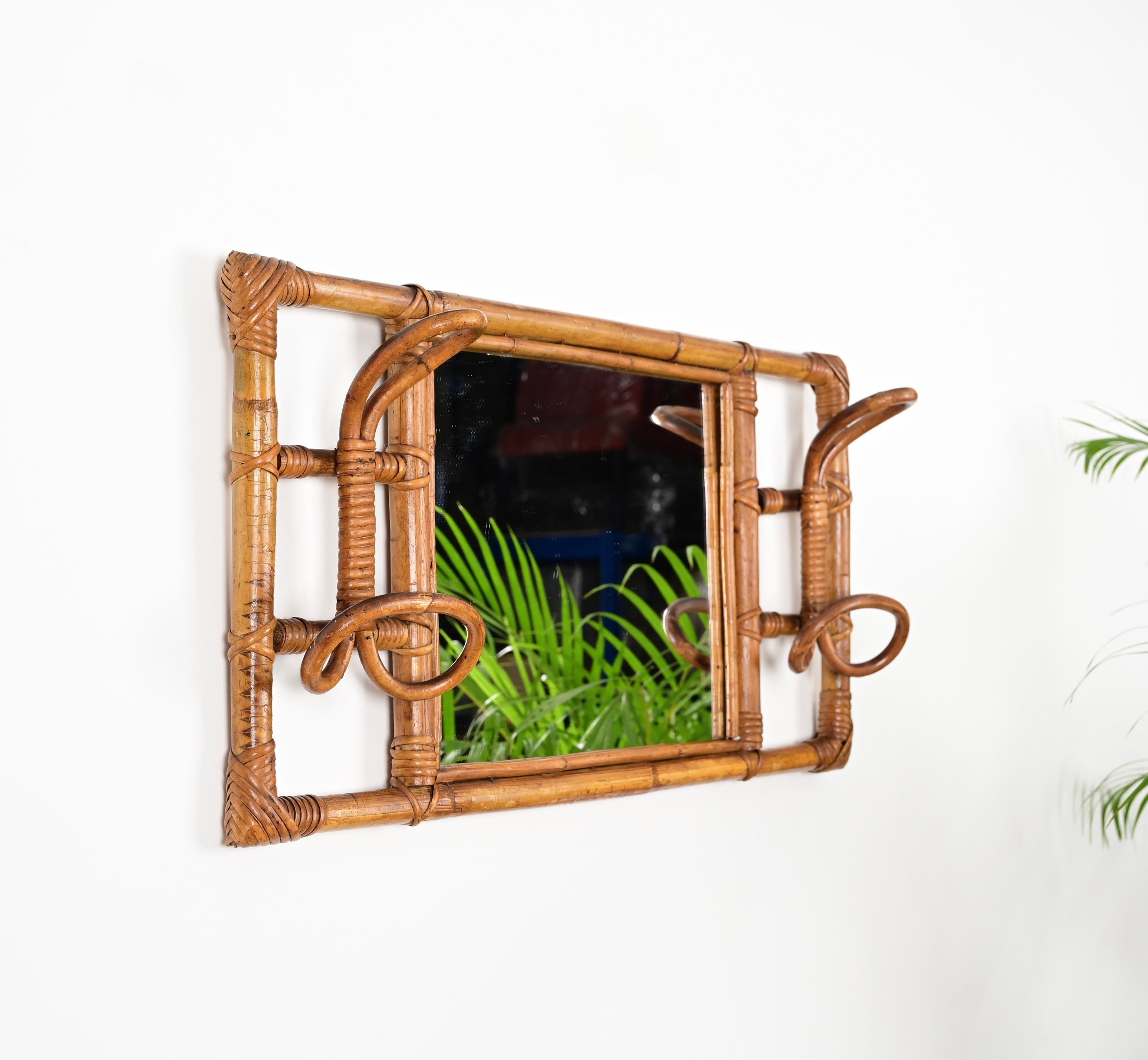 Beautiful Côte d'Azur style rectangular wall mirror with two side coat hooks in curved rattan, bamboo and hand-woven wicker. This lovely mirror was produced in Italy during the 1960s.

This unique mirror features a rectangular frame in bamboo with a