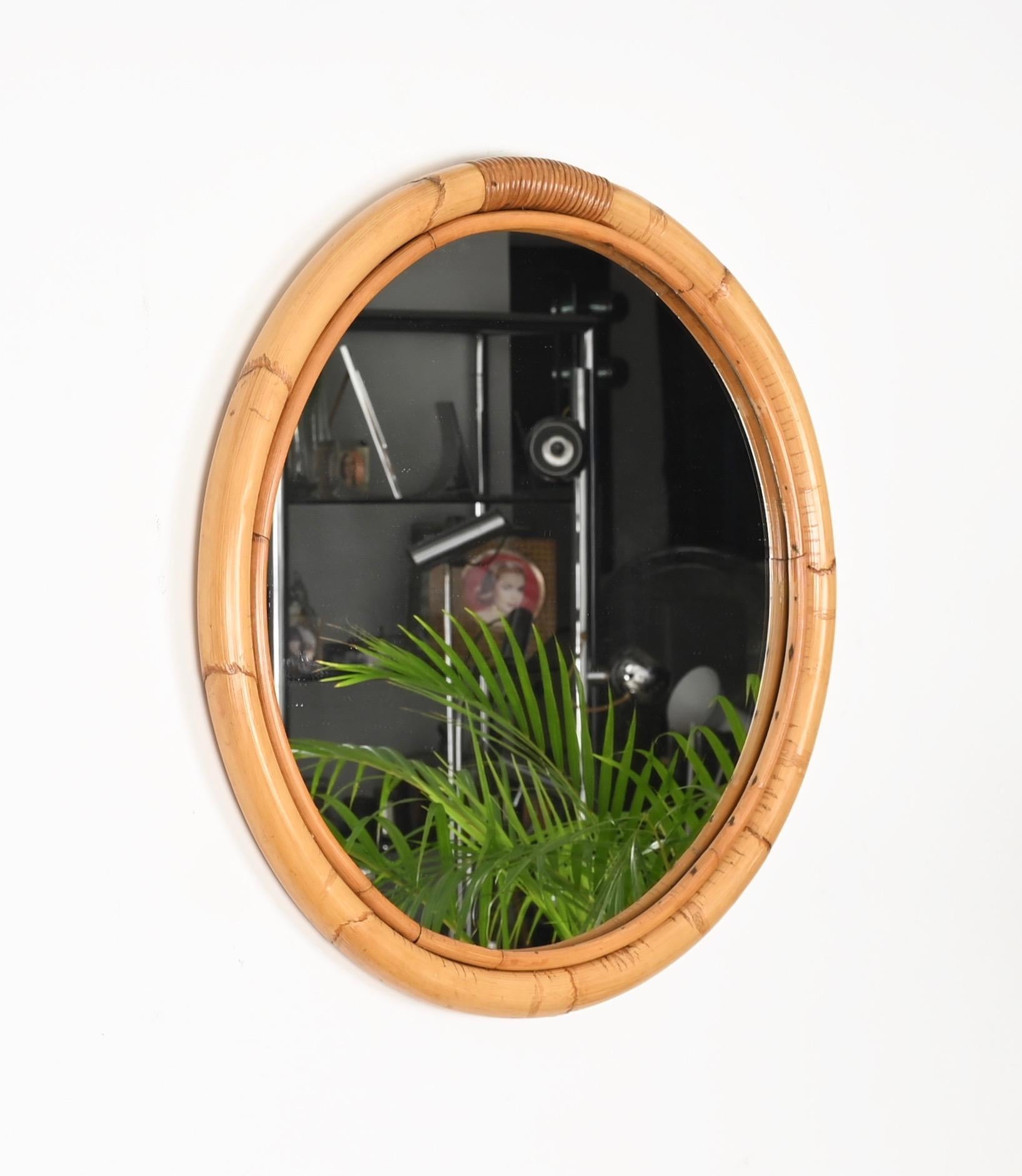 Beautiful Mid-Century round mirror with a double frame in curved bamboo canes and woven wicker. This fantastic item was produced in Italy in the 1970s.

The mirror features a double round frame, the external one in curved bamboo and the inside one