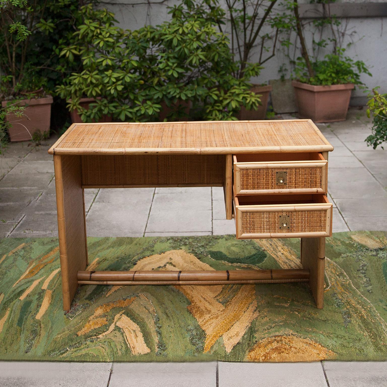 Elegant French Riviera style desk made of bamboo and wicker with two side drawers with recessed brass handles by the well-known manufacturer Dal Vera, Italy 1960s. A timeless desk whose design with the woven material and the bamboo has both a