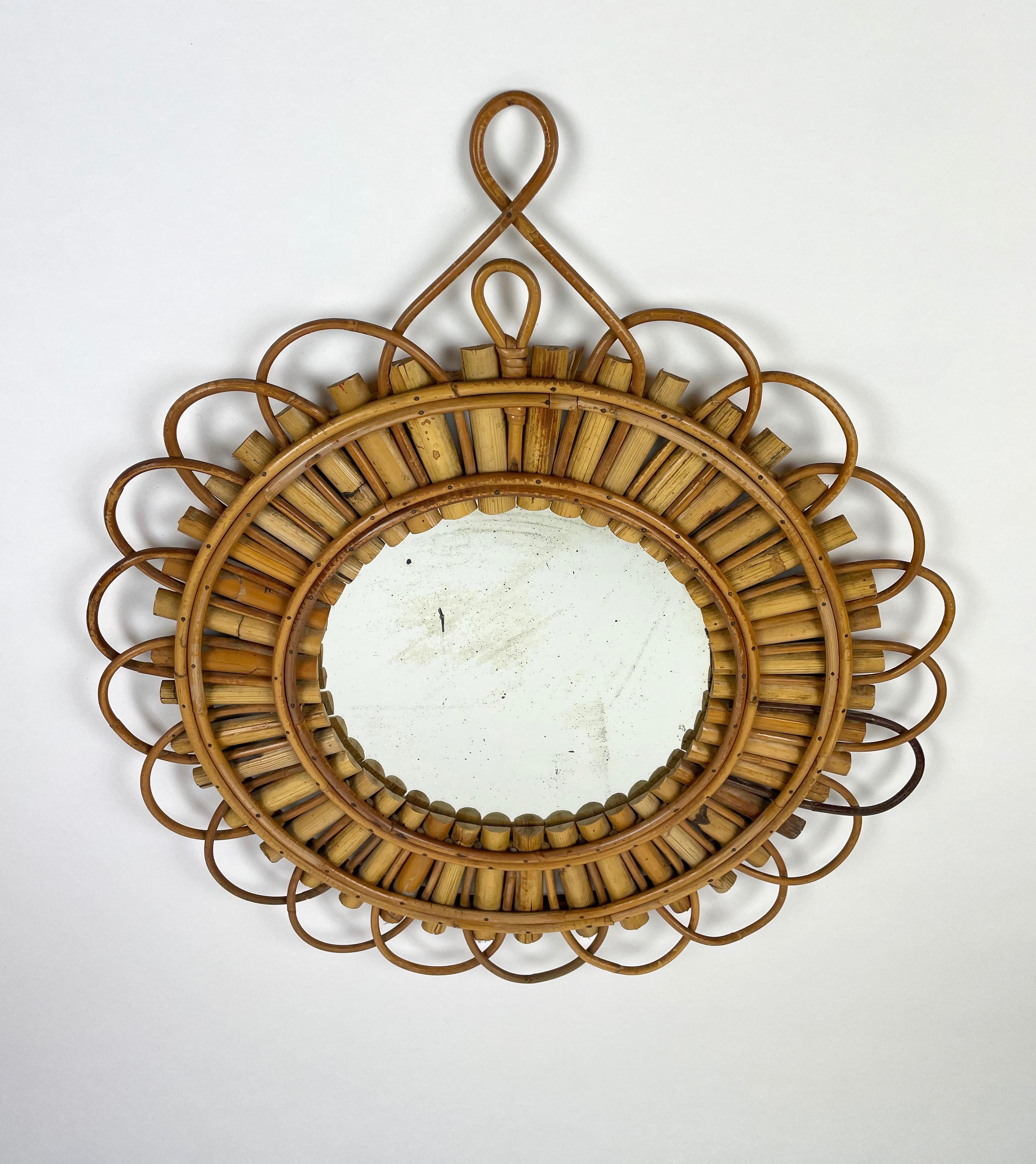 Wall mirror sunburst shaped in rattan bamboo, French Riviera, 1960s. The mirror has vintage-effect due to its age. 

Measures: Mirror diameter 25 cm.