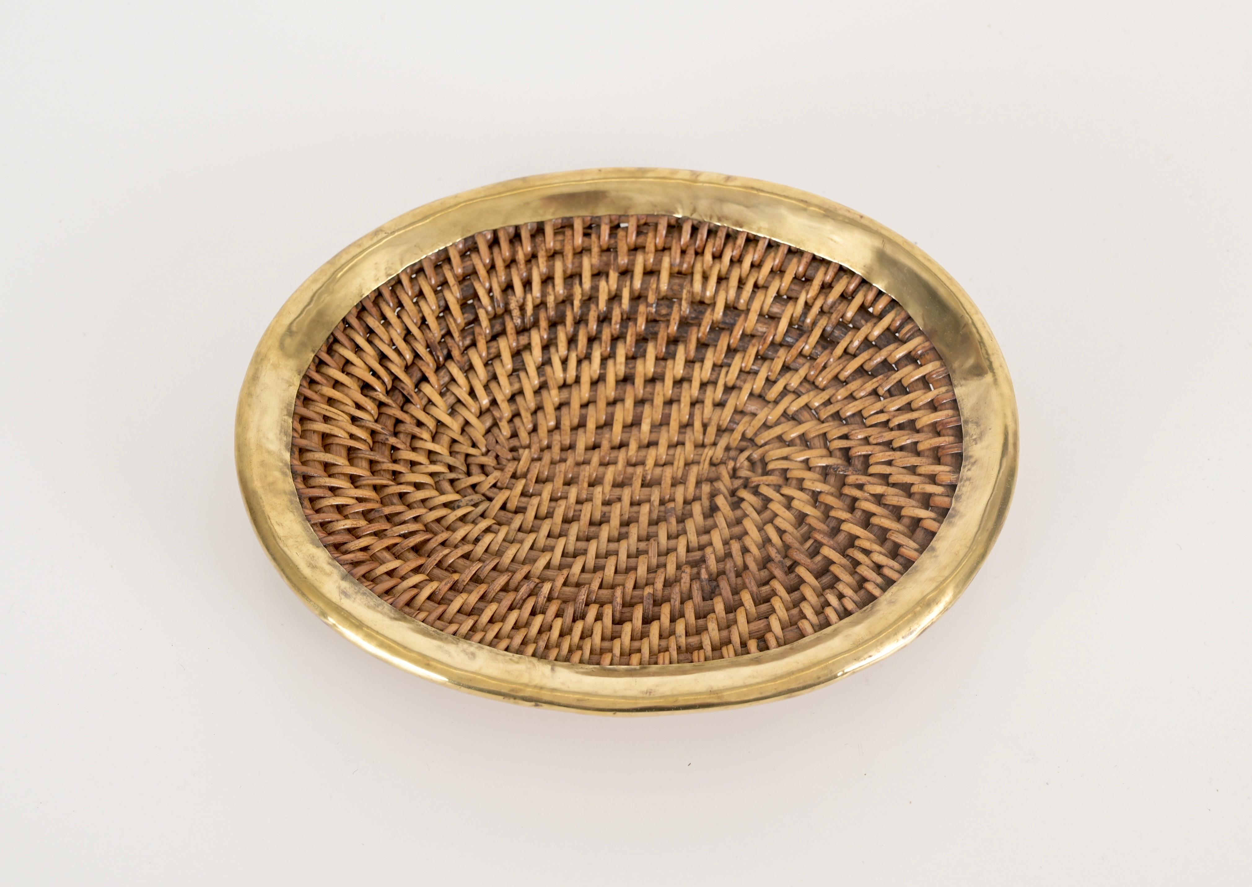 Beautiful vide-poche or decorative bowl fully made in woven rattan wicker and brass. This elegant French Riviera style object was made in Italy during the 1970s.

This stunning vide-poche has an oval-shaped tray made in woven rattan wicker and