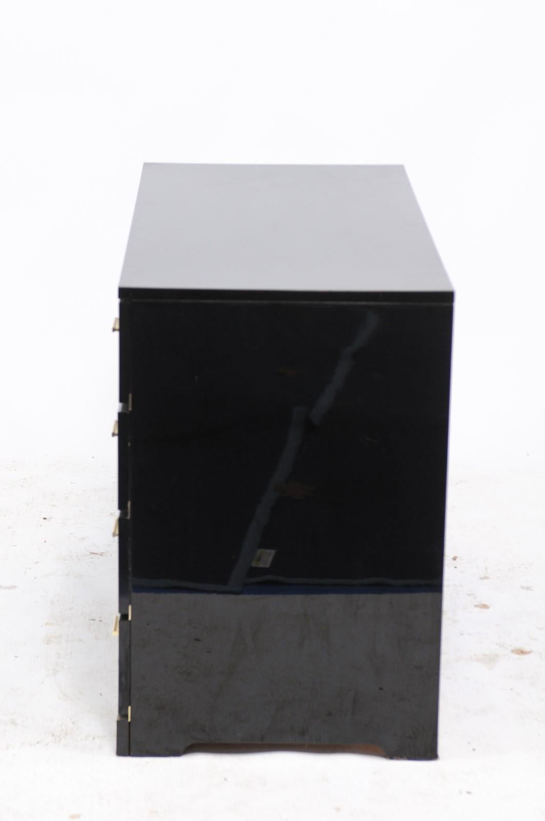 A French Roche Bobois black lacquer dresser from the mid-20th century, with four drawers and brass hardware. We found this vintage 1960s Roche Bobois black lacquered dresser in Paris and fell in love with the sleek lines and the subtle brass