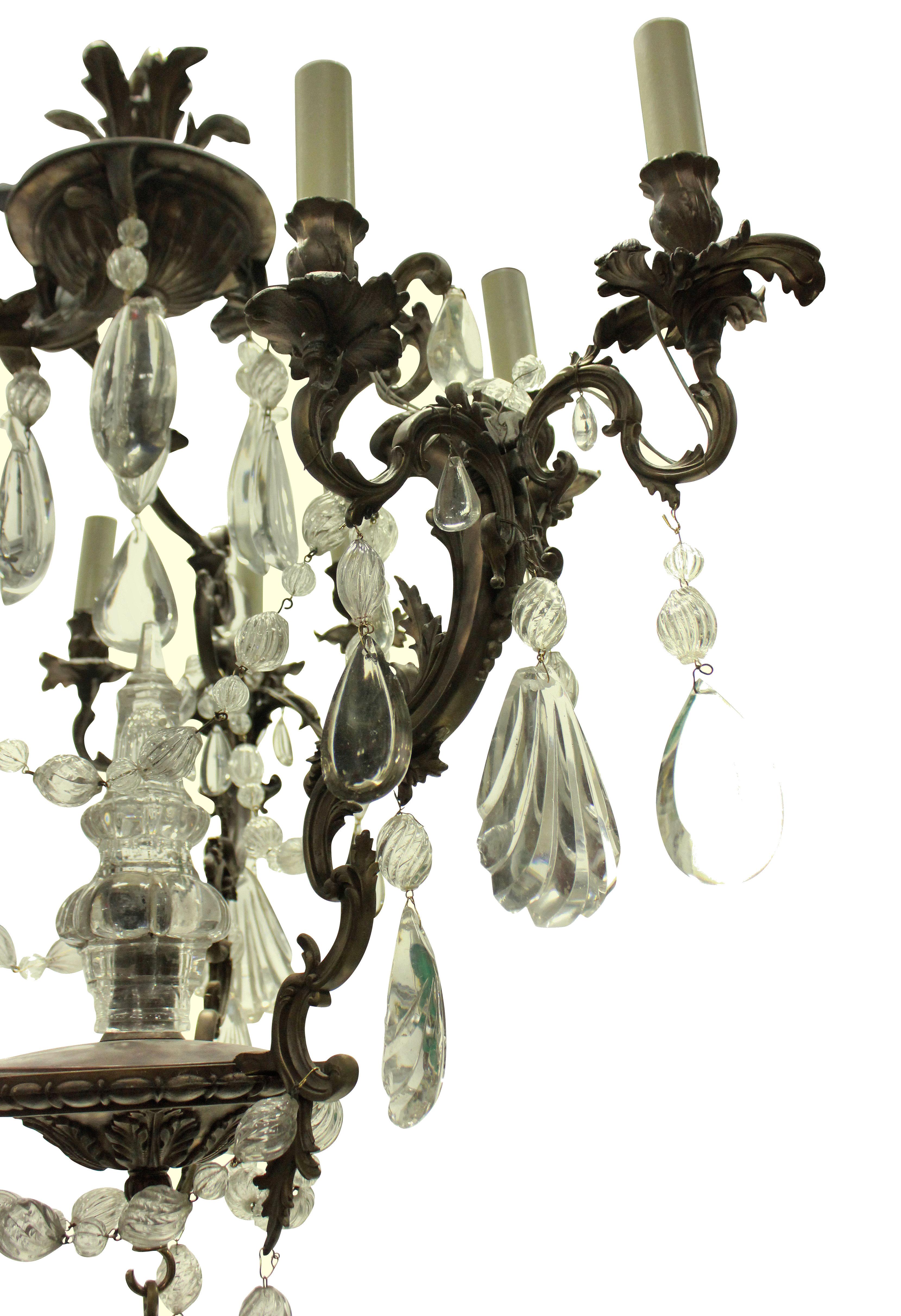 A French Rococo bronze chandelier hung throughout with interesting cut and blown glass drops and swags, with a central spire.