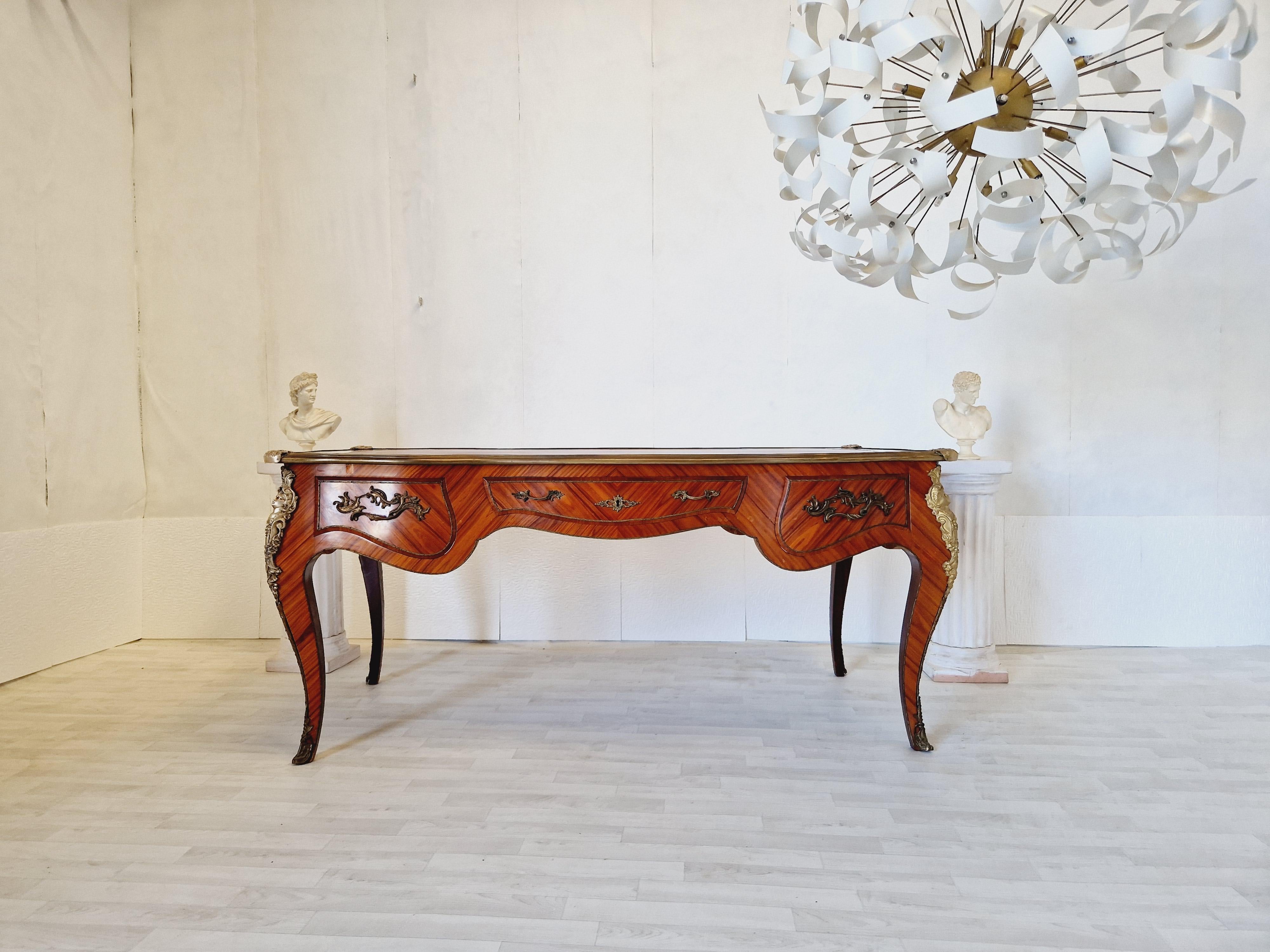 This Rococo-style writing desk was crafted in the 1950s, featuring a stunning rosewood finish and intricate carvings that exude the elegance of the Louis XV style. The antique desk boasts a large rectangular top, measuring 84 cm in width and 177 cm