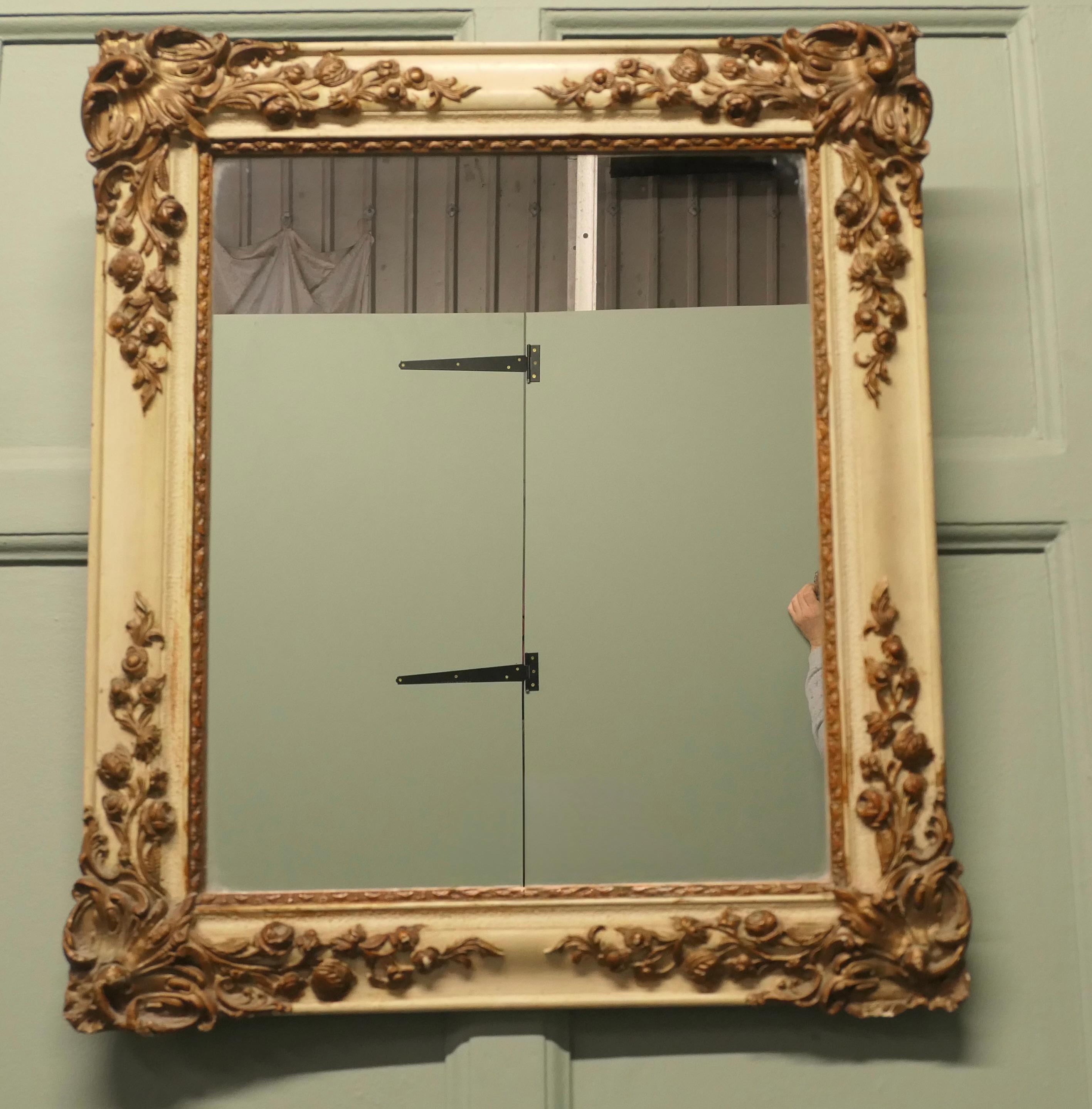 French Rococo Gilt and Cream Wall Mirror

The mirror has a superb 3” wide Rococo style Cream and Gilt Frame which has a backward slope with very ornate gesso decoration featuring rosebuds and large scrolling leaves
The mirror glass is in good