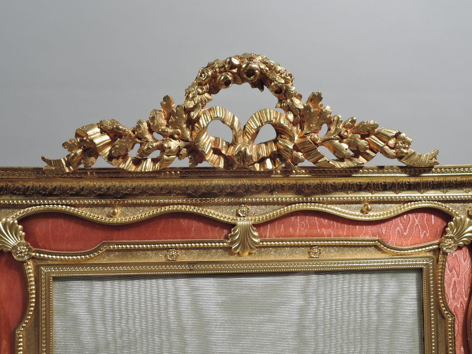 Turn-of-the-century French gilt-bronze picture frame. Rectangular window in same surround with raised beaded, leaf, and guilloche borders and scallop shells applied over ribbon border in pink guilloche enamel. Wreath-and-ribbon crown. With glass,