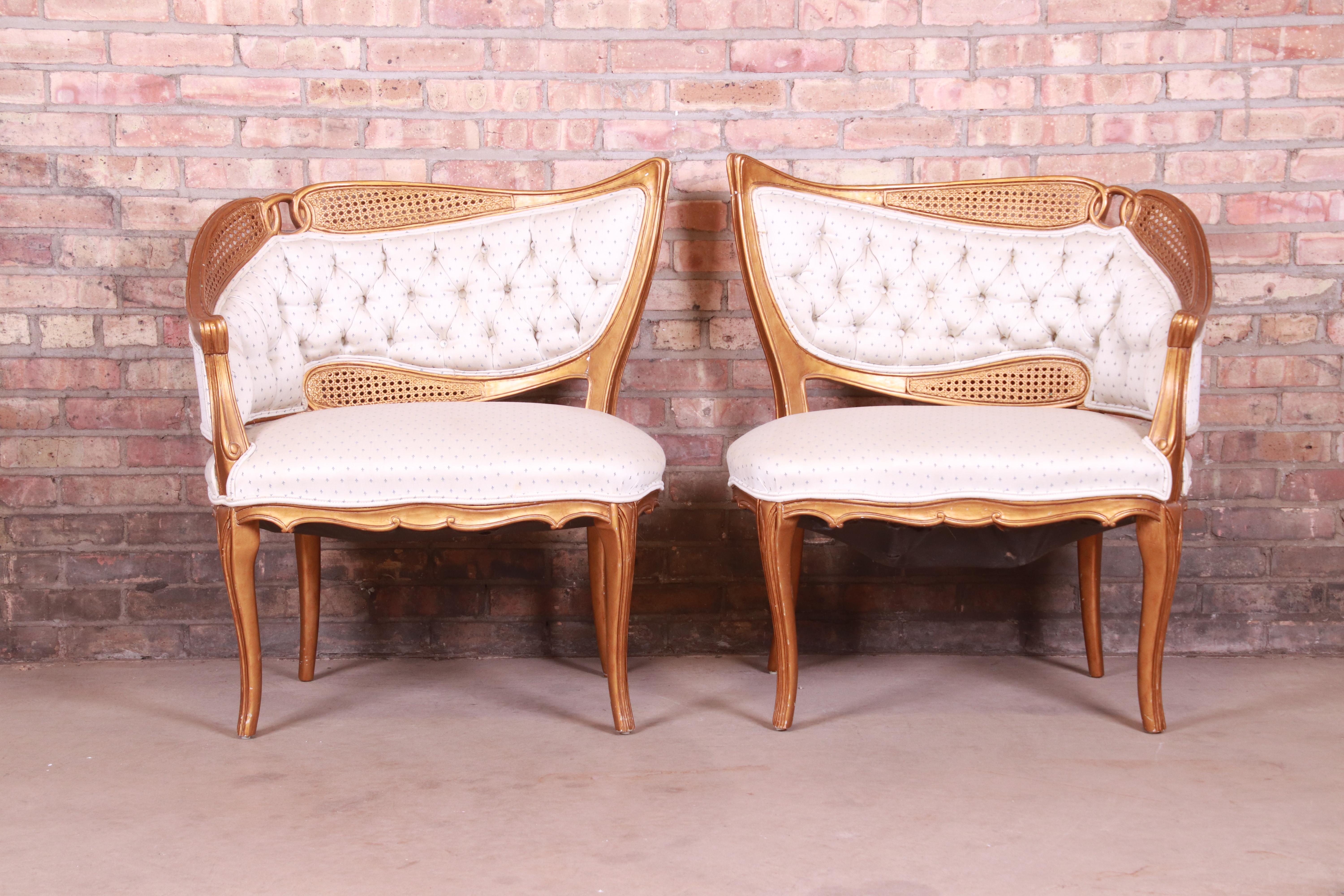 A gorgeous pair of French Rococo Louis XV style gilded fireside club chairs or lounge chairs

In the manner of Grosfeld House,

Mid-20th century

Giltwood and caning, with upholstered seats and backs.

Measures: 31