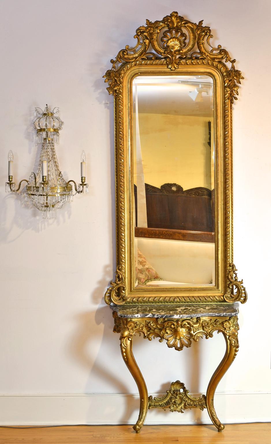 Miroir et console en bois doré de style rococo. La console est une pièce rococo d'époque Louis XV (vers la fin des années 1700), ornée de sculptures de rocaille, d'acanthe et de fleurs, dont des coquilles Saint-Jacques et des marguerites, avec des