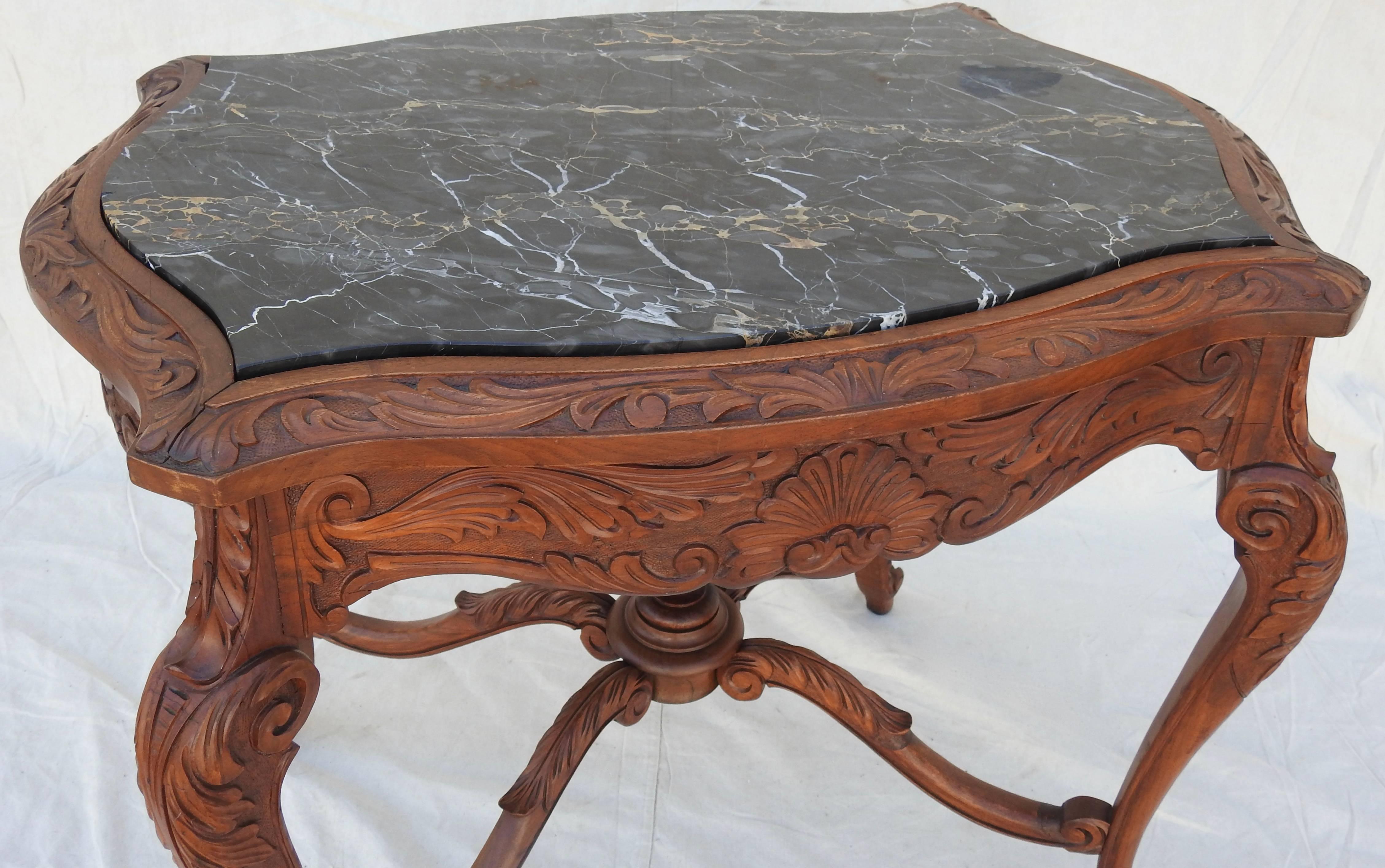 Offering this beautiful French Rococo marble-top walnut parlor table. Stunning hand carved detail of scrollwork, foliate and floral designs grace the skirt of this table. It is topped with black marble with veins of silver gray and brown. The marble