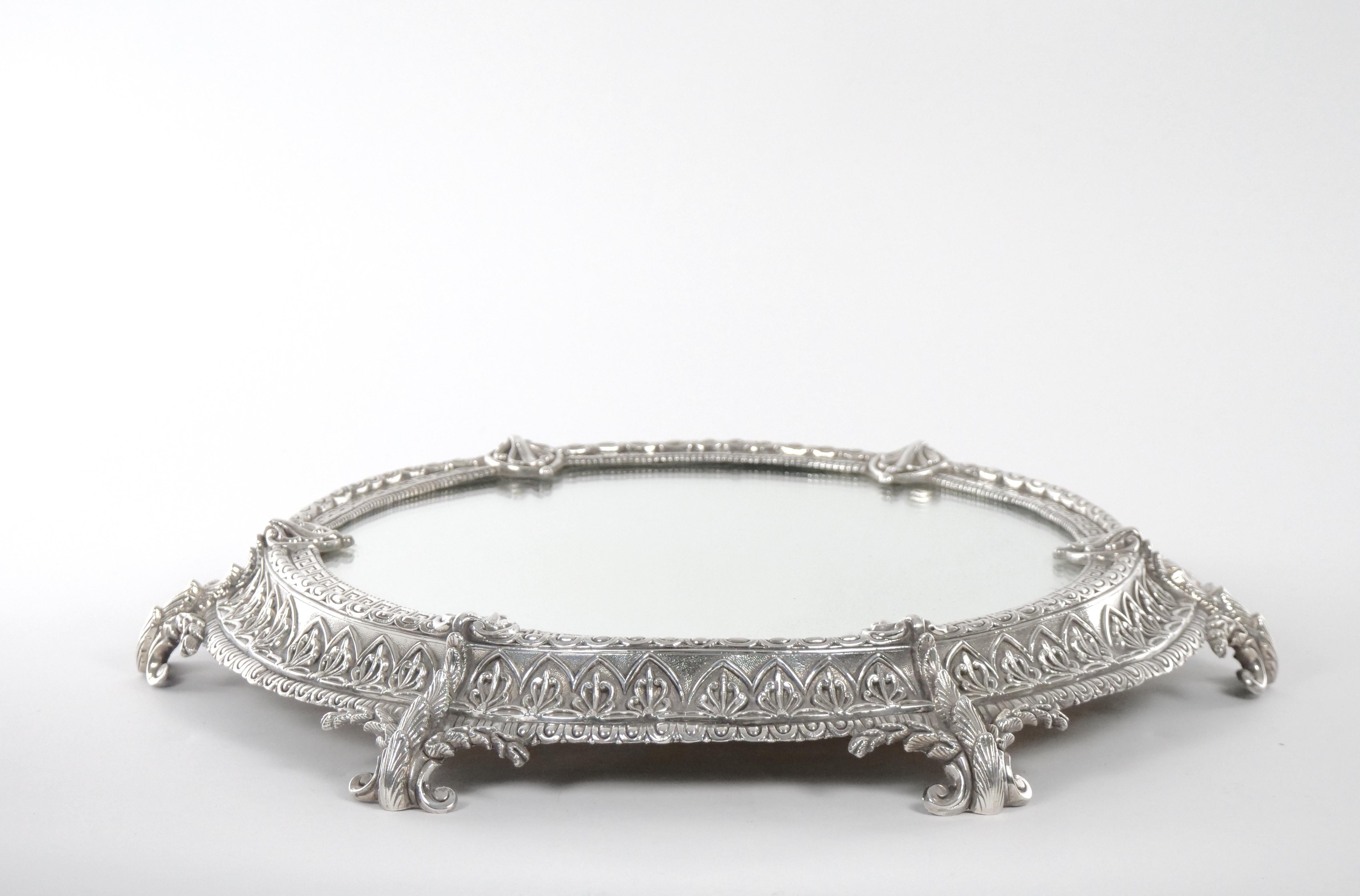 19th century French Rococo Revival silver plate oval shape footed centerpiece plateau. The plateau features a curvilinear cartouche with 6 leaf-mounted scroll supports. The plated frame is heavily decorated with a round trim interlace greek key,