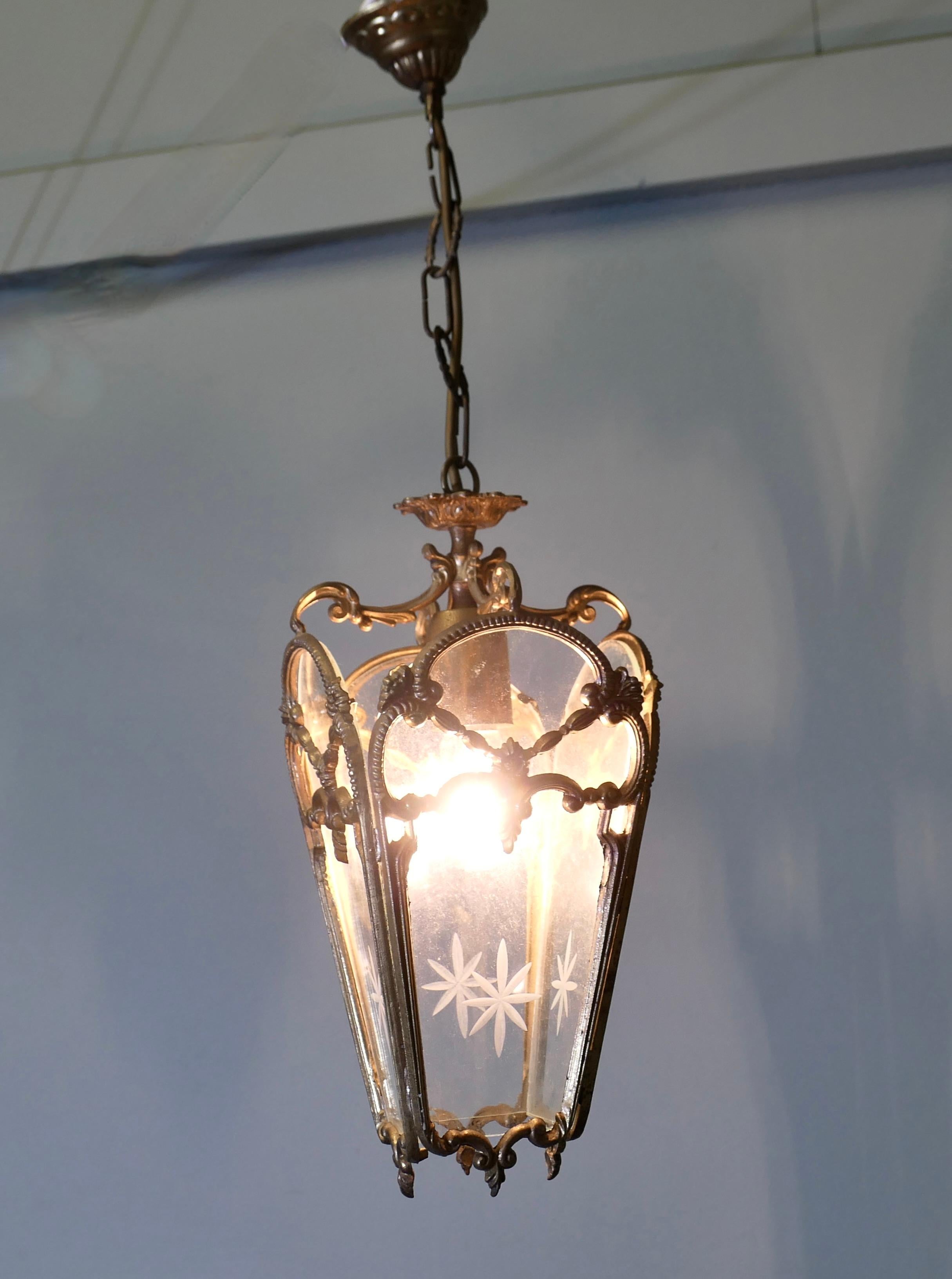 French Rococo Style Brass and Etched Glass Lantern Hall Light

A superb quality brass lantern, the light has 4 clear glass panels, these are each etched with a starburst at the centre

The lantern is decorated in the French style  and it hangs from