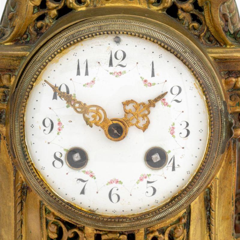 French Rococo Style Brass Mantel Clock, late 19th century, with fleur-de-lis finial, pierced scroll form body on six legs, with painted white porcelain clock face. 15.5