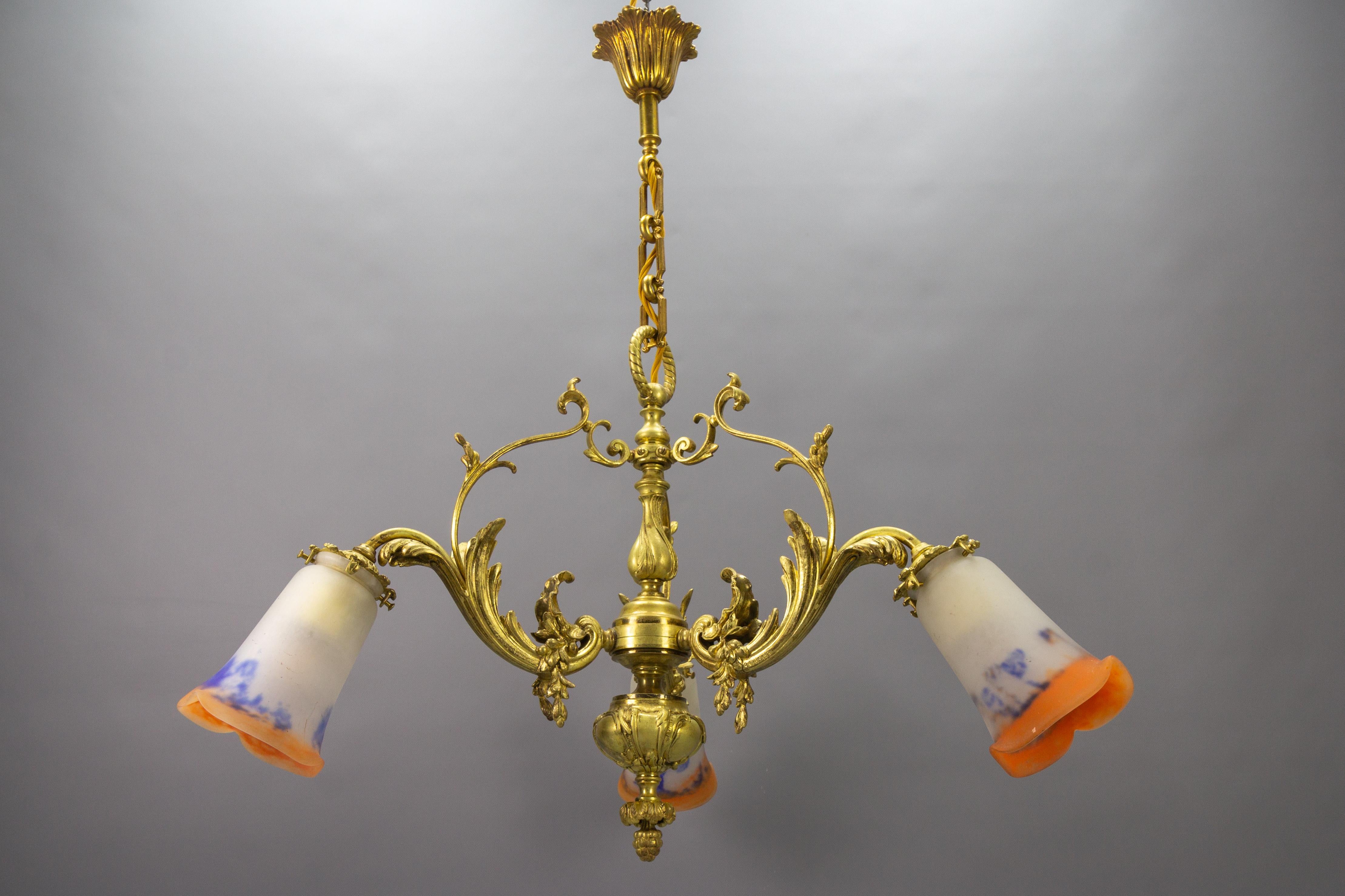 French Louis XV or Rococo style bronze and Noverdy glass three-light chandelier, from circa 1920.
This absolutely splendid antique chandelier features a beautifully shaped bronze frame adorned with acanthus leaves, and three arms that are numbered,