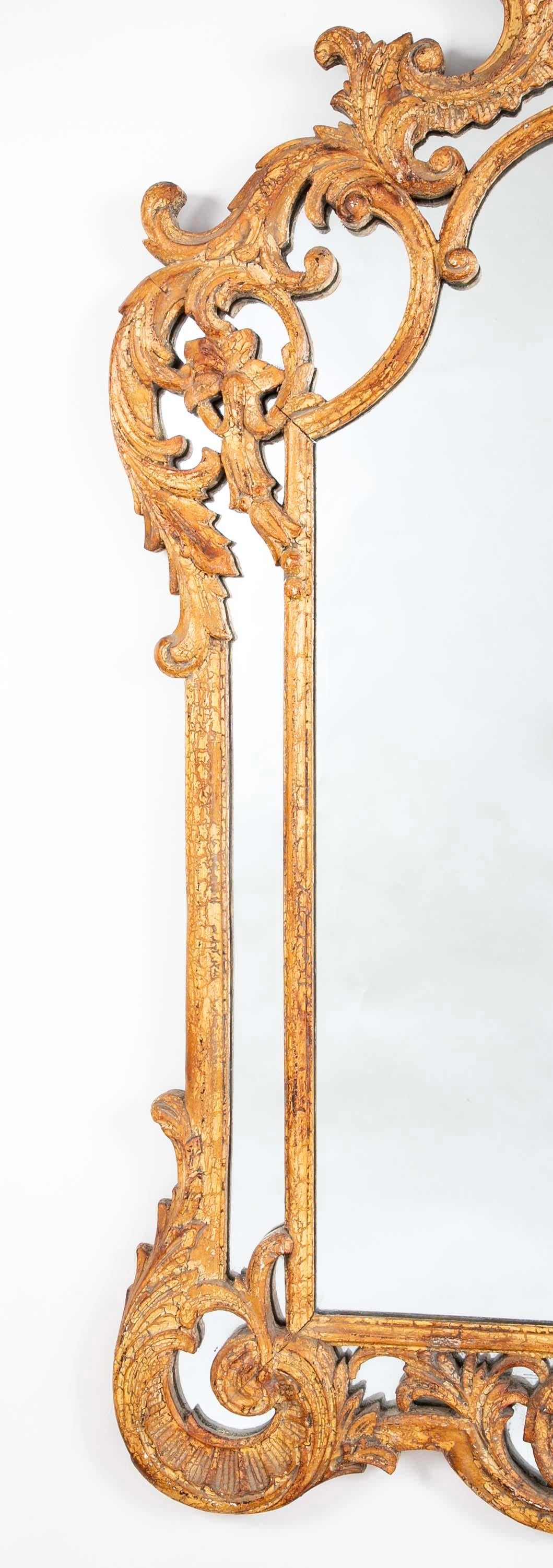Miroir en bois sculpté à la main de style rococo français avec une magnifique patine de surface. Le cadre ajouré est sculpté de feuilles d'acanthe, d'ogives et de décorations florales, avec une étoile sculptée au centre de la couronne. 
La sculpture