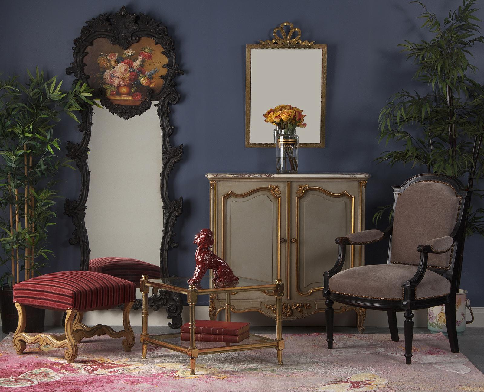 A French Rococo style full length mirror that was painted in black over the original giltwood frame. The frame has abundant carvings of foliage, roses, acanthus leaves and scrolls. The painting represents a vase with colorful flowers. A stylish