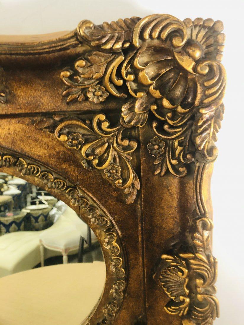 Magnifique miroir mural de style rococo français du 20e siècle (environ les années 1940). Le miroir présente un cadre rectangulaire en bois doré finement sculpté à la main et une glace de forme ovale. Le miroir rehaussera le style de n'importe