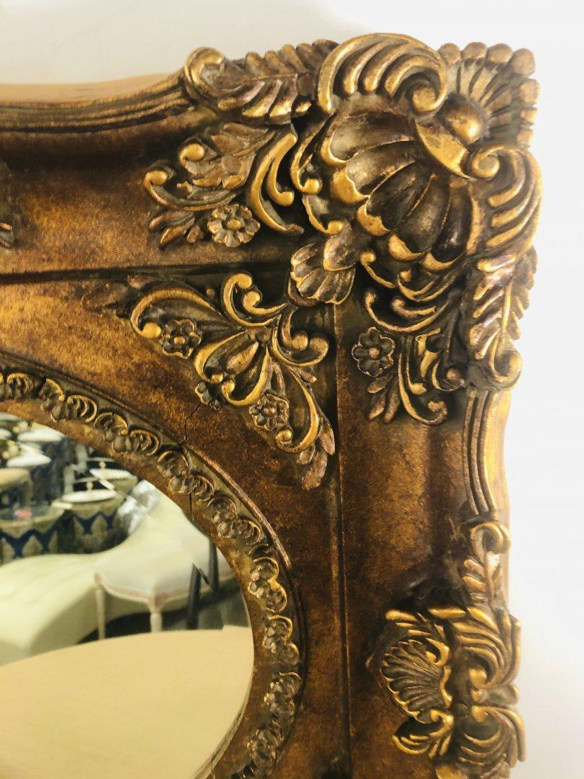 A beautiful 20th century (approximately 1940's) French Rococo style wall mirror. The mirror features very finely hand carved wood gilded rectangular frame and an oval shaped mirror glass. The mirror will elevate the style of any room and will add