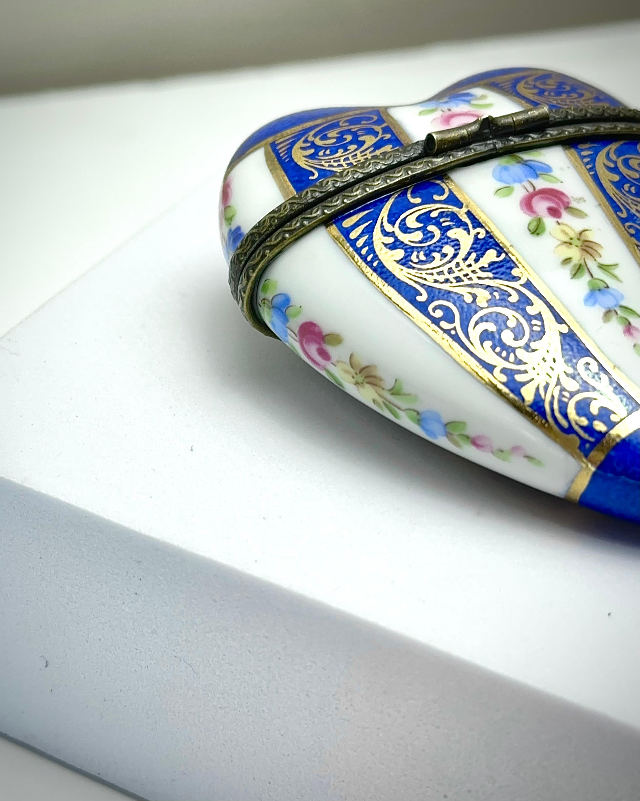 Limoges porcelain heart shaped trinket box. Hand-crafted in France around the late 1980’s

Finely decorated in the french rococo style; the body of the heart decorated with lapis lazuli blue stripes highlighted with gold gilt rococo scrolls.
