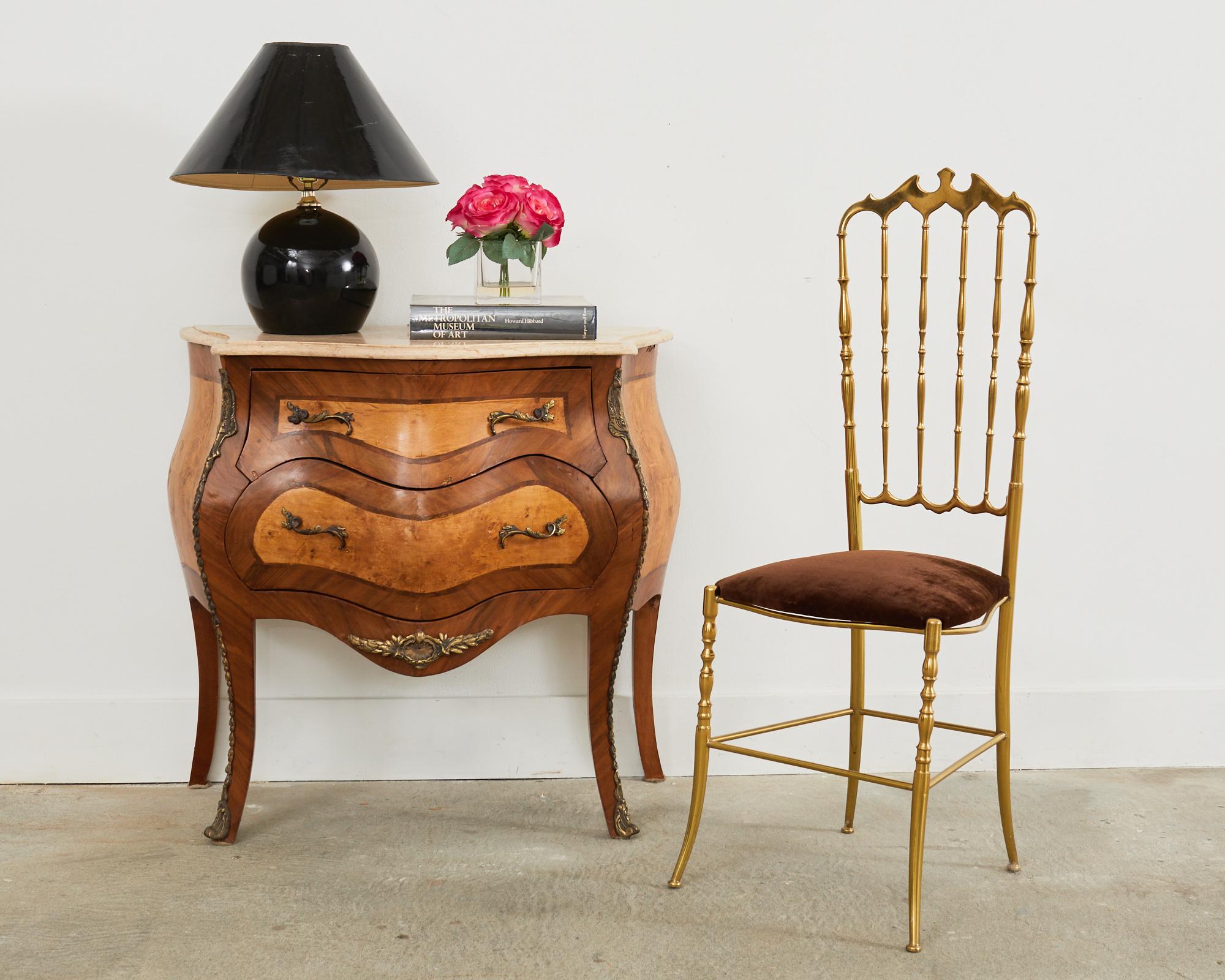 Opulent French bombe chest featuring a marble top. Beautifully crafted with rich veneers of mahogany with burl inlay. The gracefully curved frame is embellished with gilt ormolu style accents having intricate details. The case is fronted by two