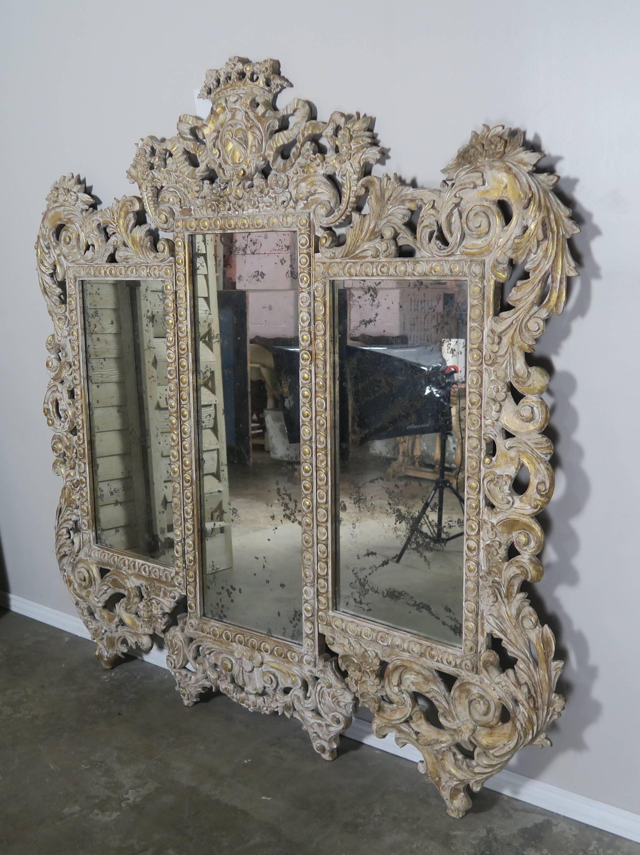 Carved painted and parcel-gilt Italian Rococo style mirror or screen. There is a crown and crest at the top of the mirror flanked by cornucopias and garlands of flowers. The frame is embellished with swirling acanthus leaves throughout. The panels
