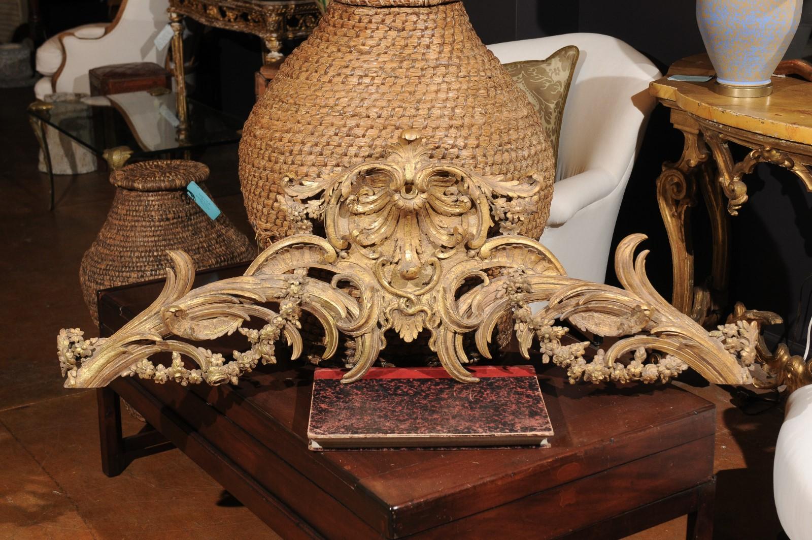 A French Rococo style parcel-gilt and carved wooden architectural swag from the 19th century, with acanthus leaves, C-scrolls and swag. Born in France during the 19th century, this architectural element features an exquisite hand-carved crest,