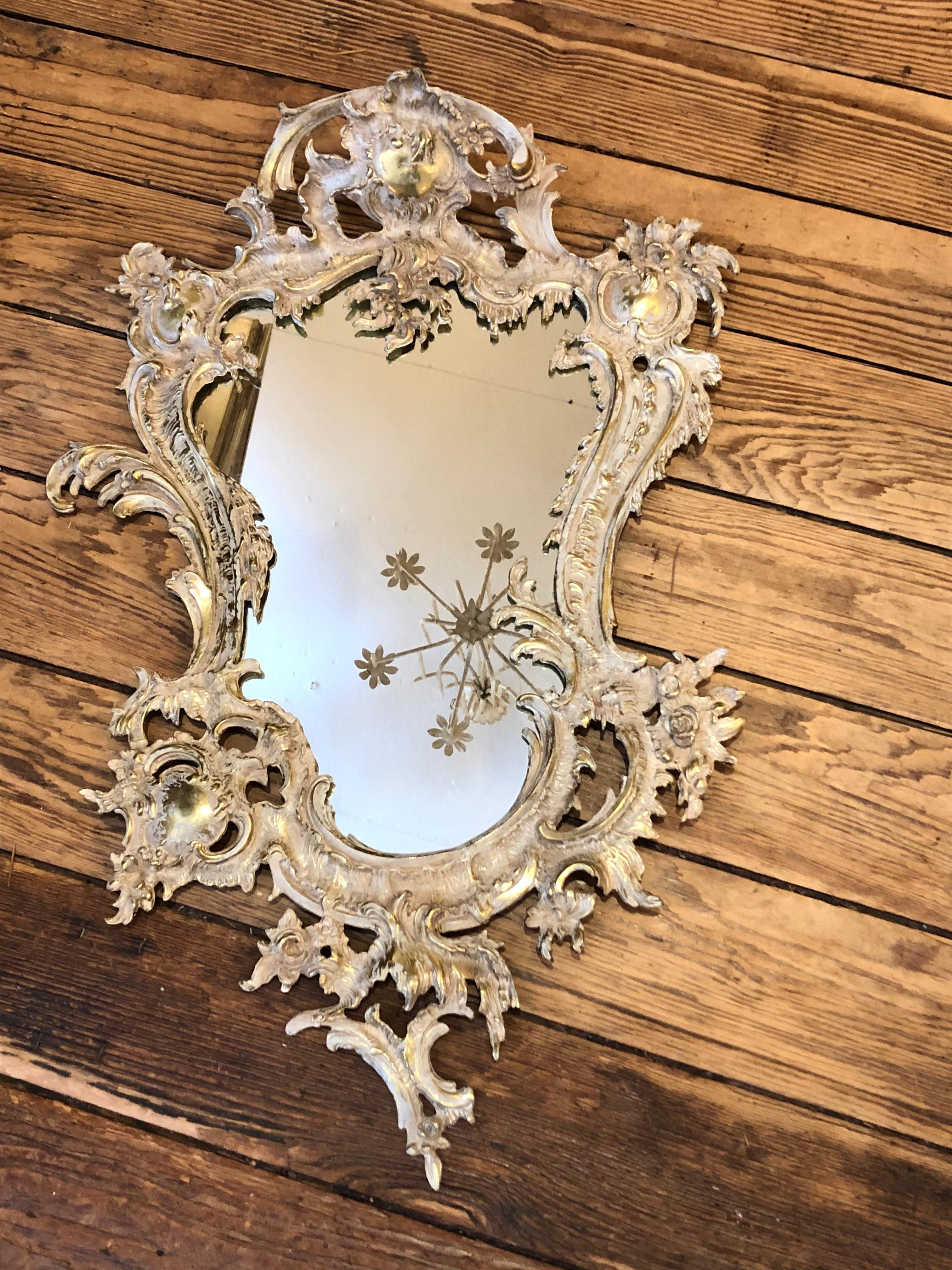 Wonderfully shaped French Rococo style relief cast brass and antiqued cartouche shaped wall mirror.