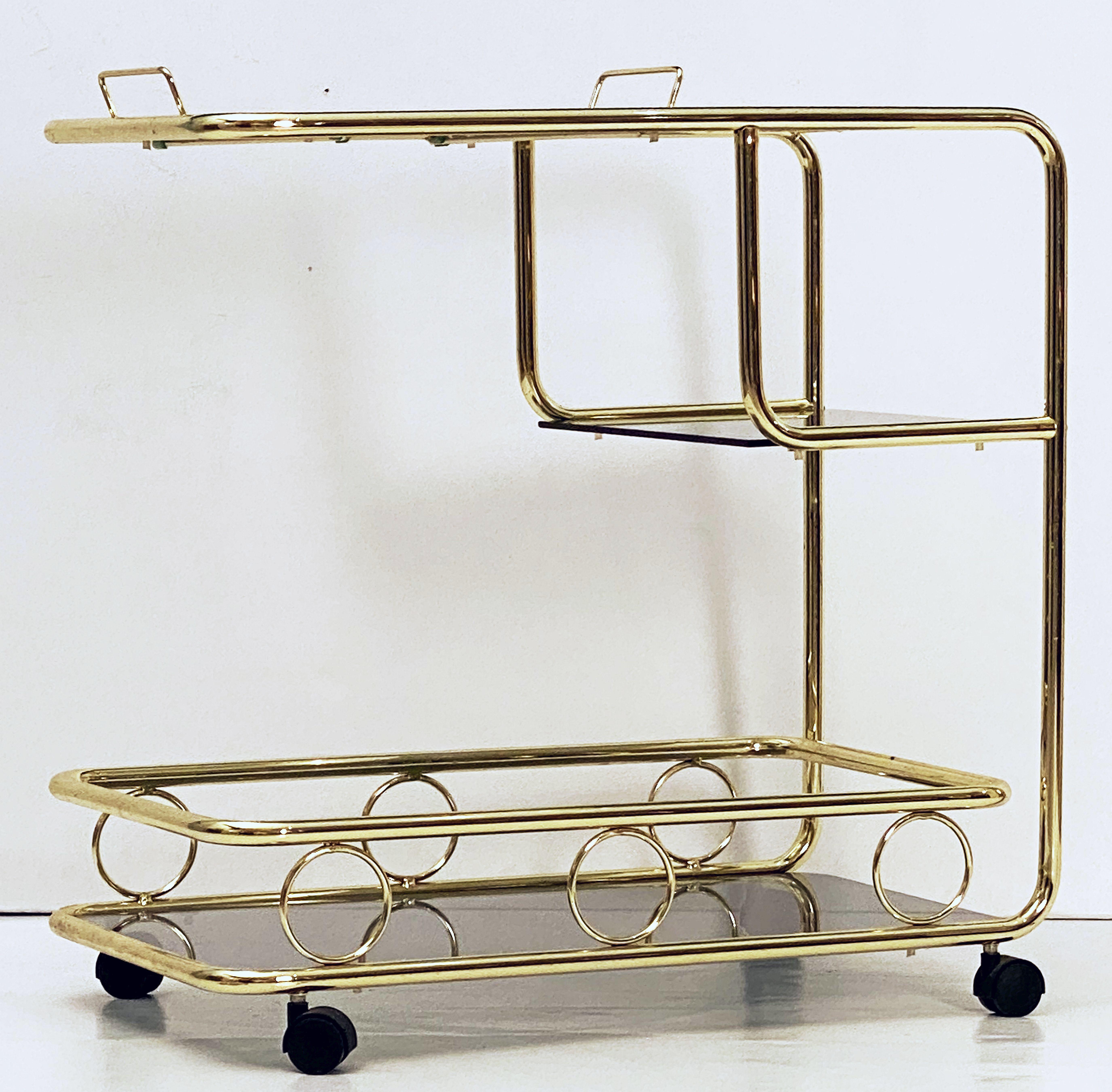 A handsome vintage French rectangular bar cart table or serving trolley in brass, and featuring three tinted glass tiers, with bottle rack on top tier, resting on rolling caster wheels. 

Perfect for use as a side or end table.