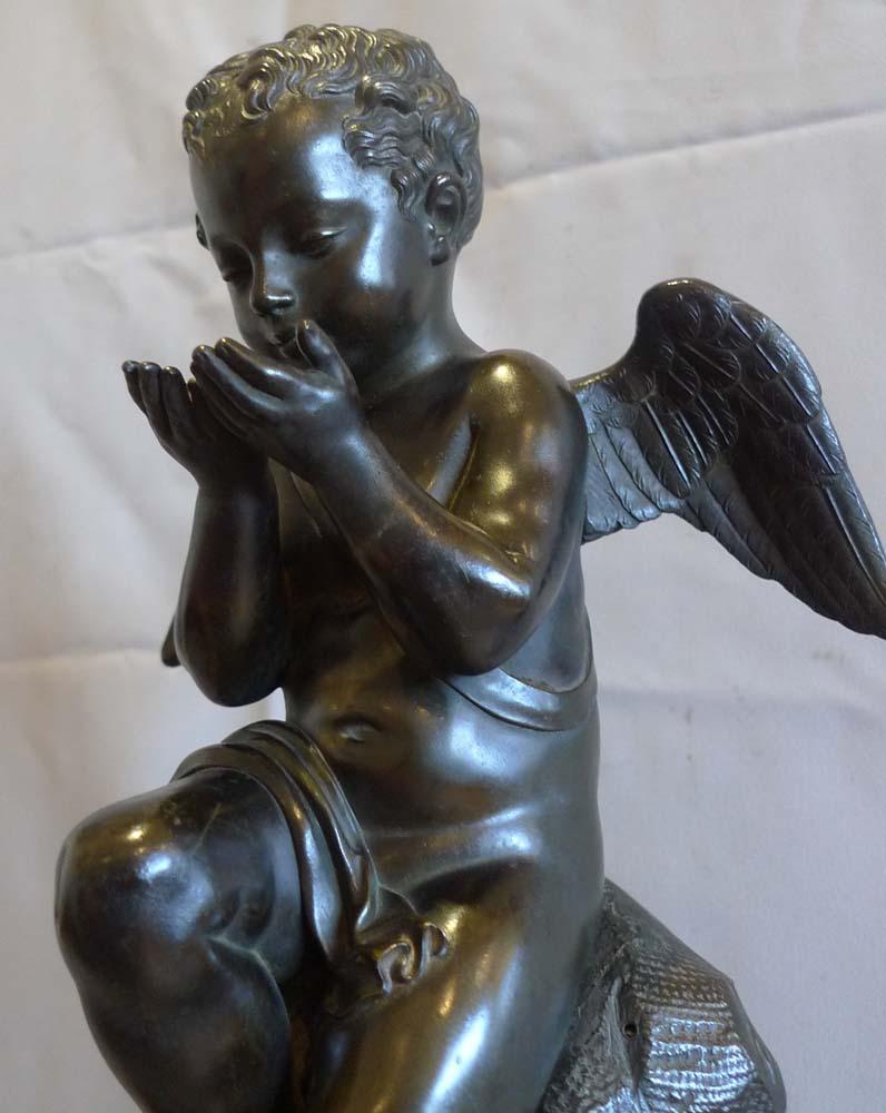 Antique mantel clock from the french Romantic period in patinated bronze, gilt bronze and antique very marble. On bracket feet and antique vert marble base the clock is surmounted by a superb patinated bronze sculpture of a seated Cupid with gilt