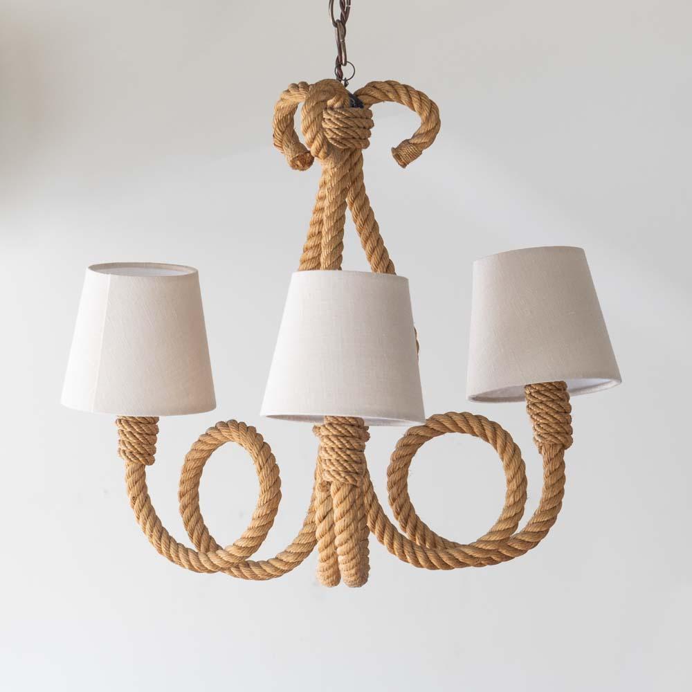 Incredible rope chandelier by French designers Adrien Audoux and Freda Minet. Beautiful three looped arms and curvy stem wrapped in rope hang on a brass chain. New tapered linen shades and newly re-wired. Original rope shows nice patina and age.