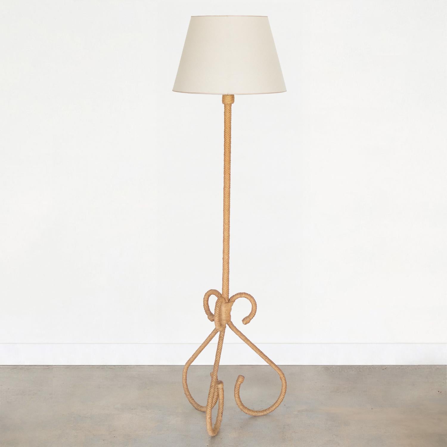 Incredible rope floor lamp by French designers Adrien Audoux and Freda Minet. Beautiful looped tripod base and stem in wrapped rope. New tapered linen shade with tan trim detail and newly re-wired. Original rope shows great patina and age. Takes one