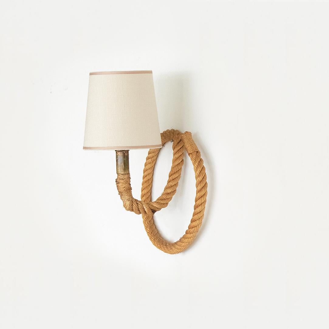 Vintage rope sconce by Audoux-Minet from France, 1950's. Brown twisted rope in circular shape with curved rope neck. New creamy linen shade with tan trim. Brass neck detailing and newly re-wired with brown cloth twist cord, switch, and hand plug for
