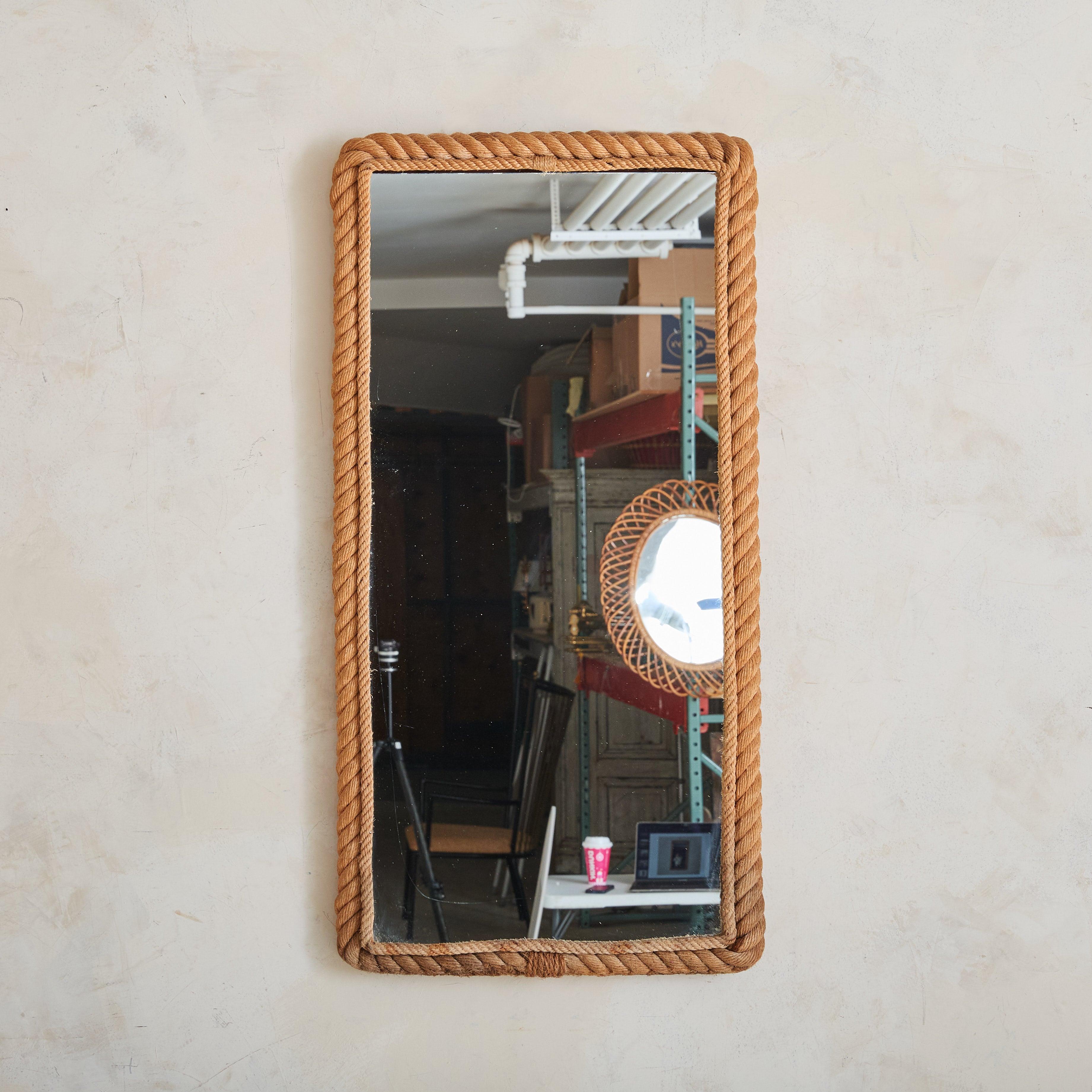 This 1950s French wall mirror—attributed to the French design duo Adrien Audoux & Frida Minet—epitomizes their signature use of woven rope. Two varying sizes of handwoven rope, rich with natural variations, are intricately laced around rectangular