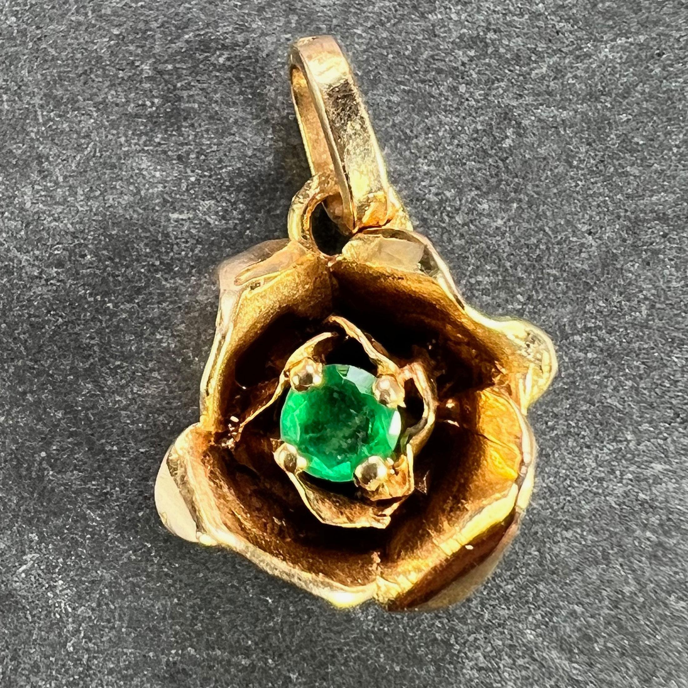A French 18 karat (18K) yellow gold charm pendant designed as a rose set to the centre with a green emerald. Stamped with the eagle’s head mark for 18 karat gold and French manufacture, and an unknown maker’s mark.

Dimensions: 1.2 x 1 x 0.53 cm