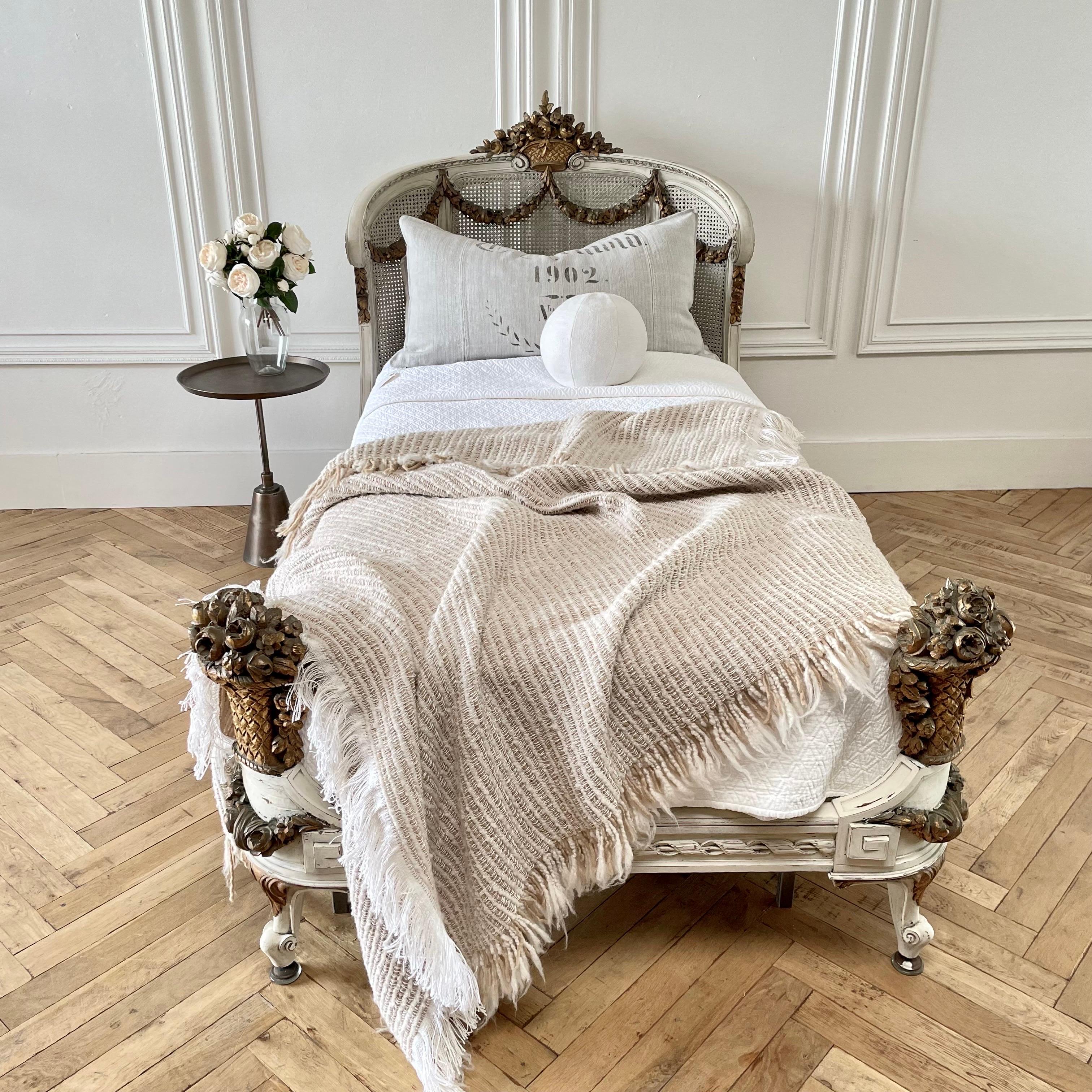 Pair of vintage painted and giltwood cane french beds.
Painted in a soft oyster white with subtle distressing, and antique patina.
Cane is all in tact with no major breaks or damage.
Cane is slightly darker than the overall finish on the bed. The