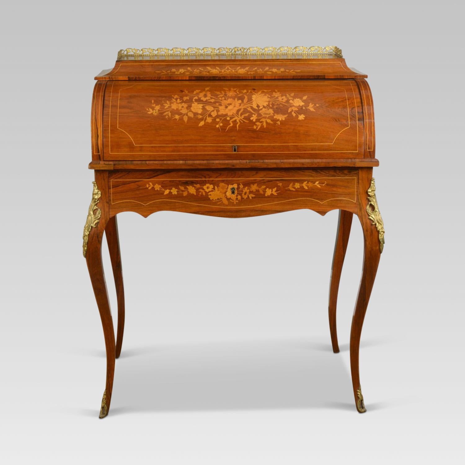 French rosewood and marquetry bureau de dame, the top with a cast brass three quarter gallery over a cylinder front inlaid with a floral bouquet in satinwood, birch and harewood, opening to reveal a pullout writing surface and with three small