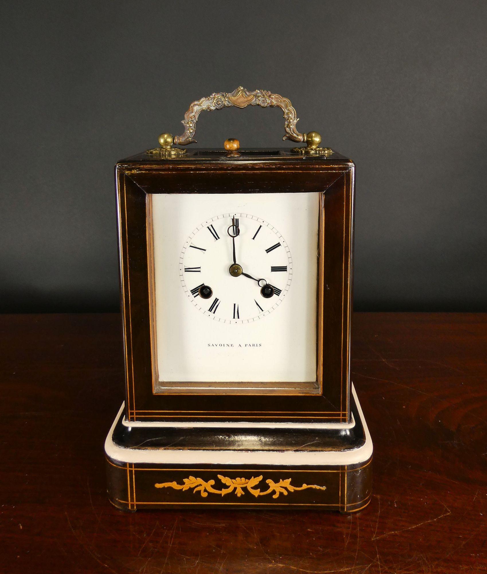 Rosewood Campaign Clock, Savoine a Paris

Rosewood campaign clock with satinwood line stringing and floral marquetry standing on a moulded plinth. Glazed viewing aperture to the to of the case and surmounted by a decorative carrying handle.
Enamel