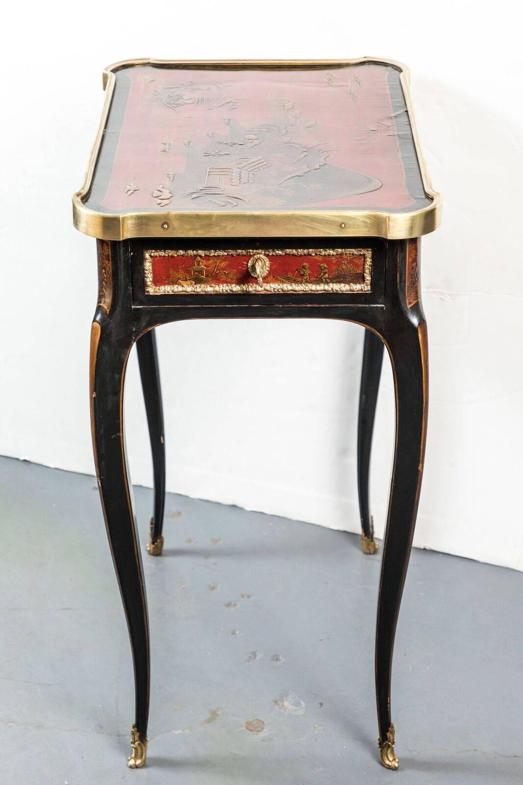 A very fine, petite, rouge and black lacquer, single drawer occasional table with a hand-painted top surrounded by a gilt bronze lip. The whole on tapered, cabriole legs terminating in ormolu feet.