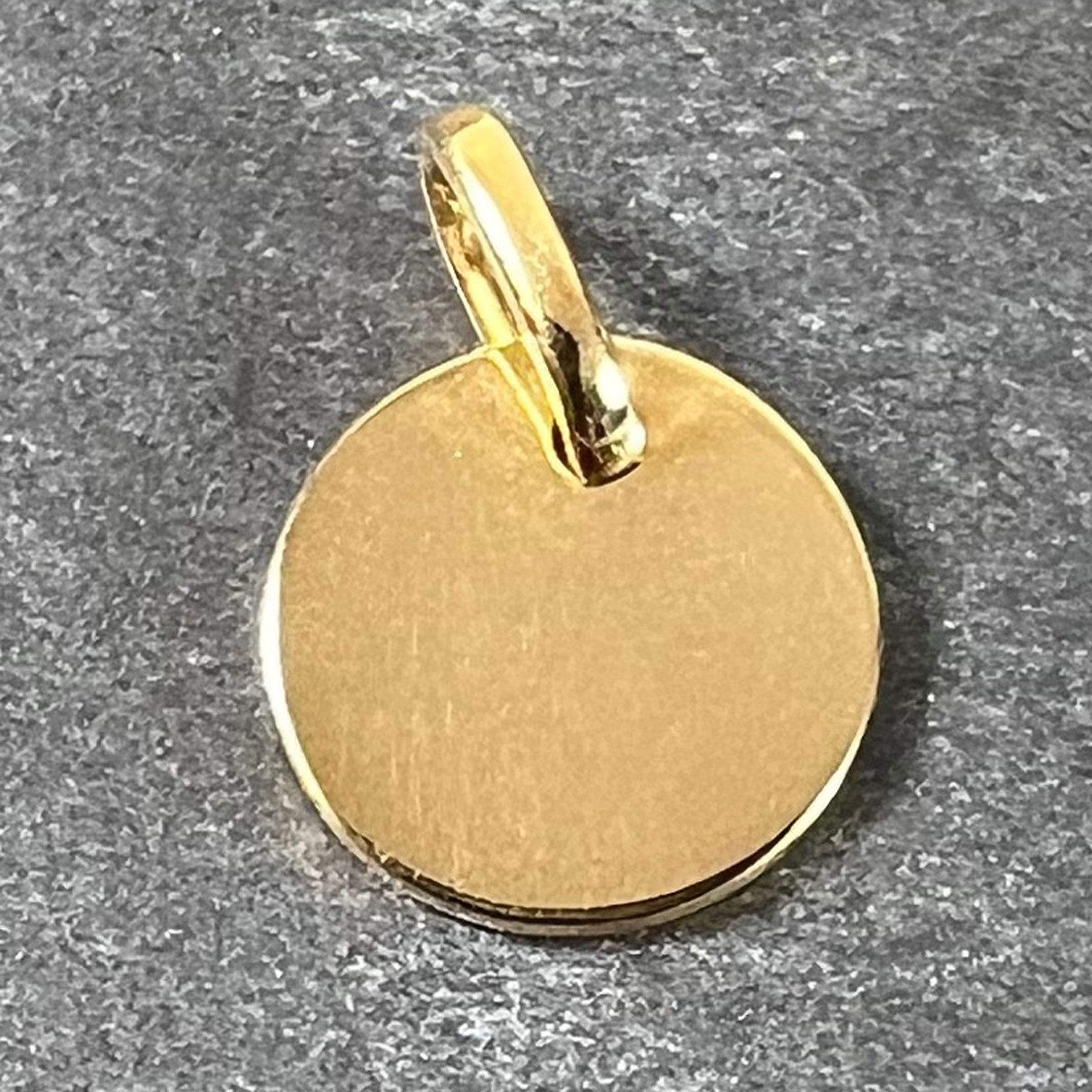 Pendentif à breloques en or jaune 18 carats (18K) conçu comme une médaille ronde polie et vierge. Estampillé de la tête d'aigle de fabrication française et de l'or 18 carats, ainsi que d'une marque de fabricant inconnue.

Dimensions : 1 x 1 x 0,08