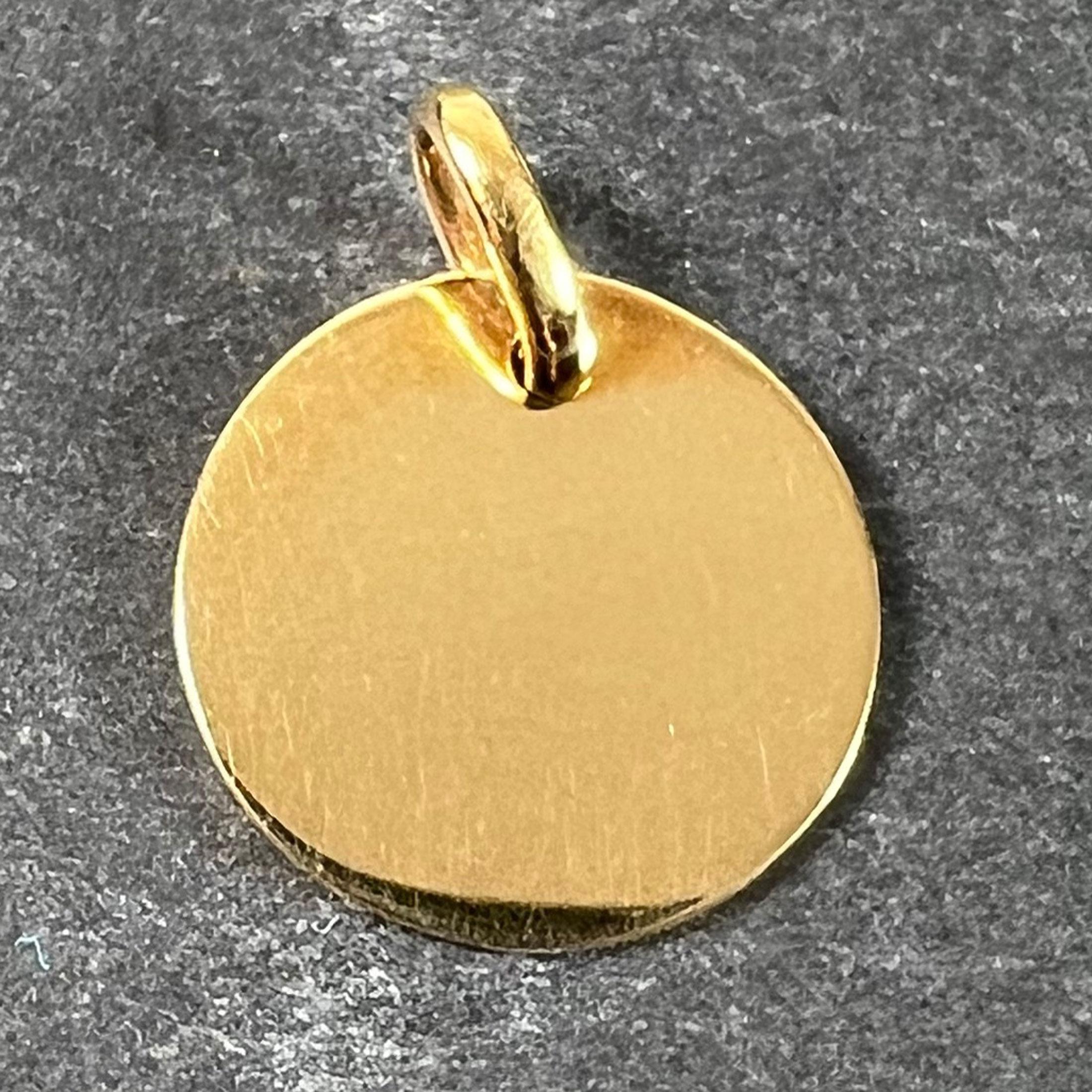 A French 18 karat (18K) yellow gold charm pendant designed as a polished round blank medal. Stamped with the eagle’s head for French manufacture and 18 carat gold and an unknown maker's mark.

Dimensions: 1.5 x 1.5 x 0.08 cm (not including jump