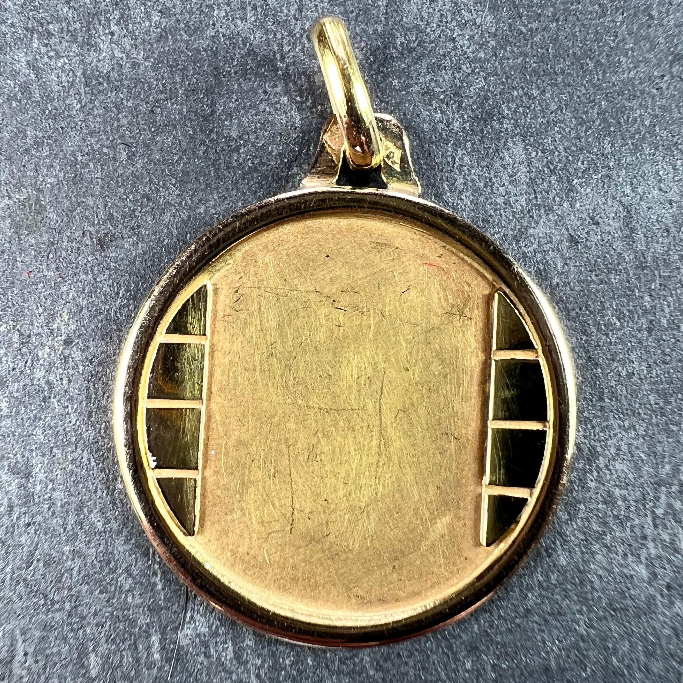 A French 18 karat (18K) yellow gold charm pendant designed as a round medal with a vertical brick motif to either side of the central matt section with a polished surround. Stamped with the eagle’s head for French manufacture and 18 carat gold and