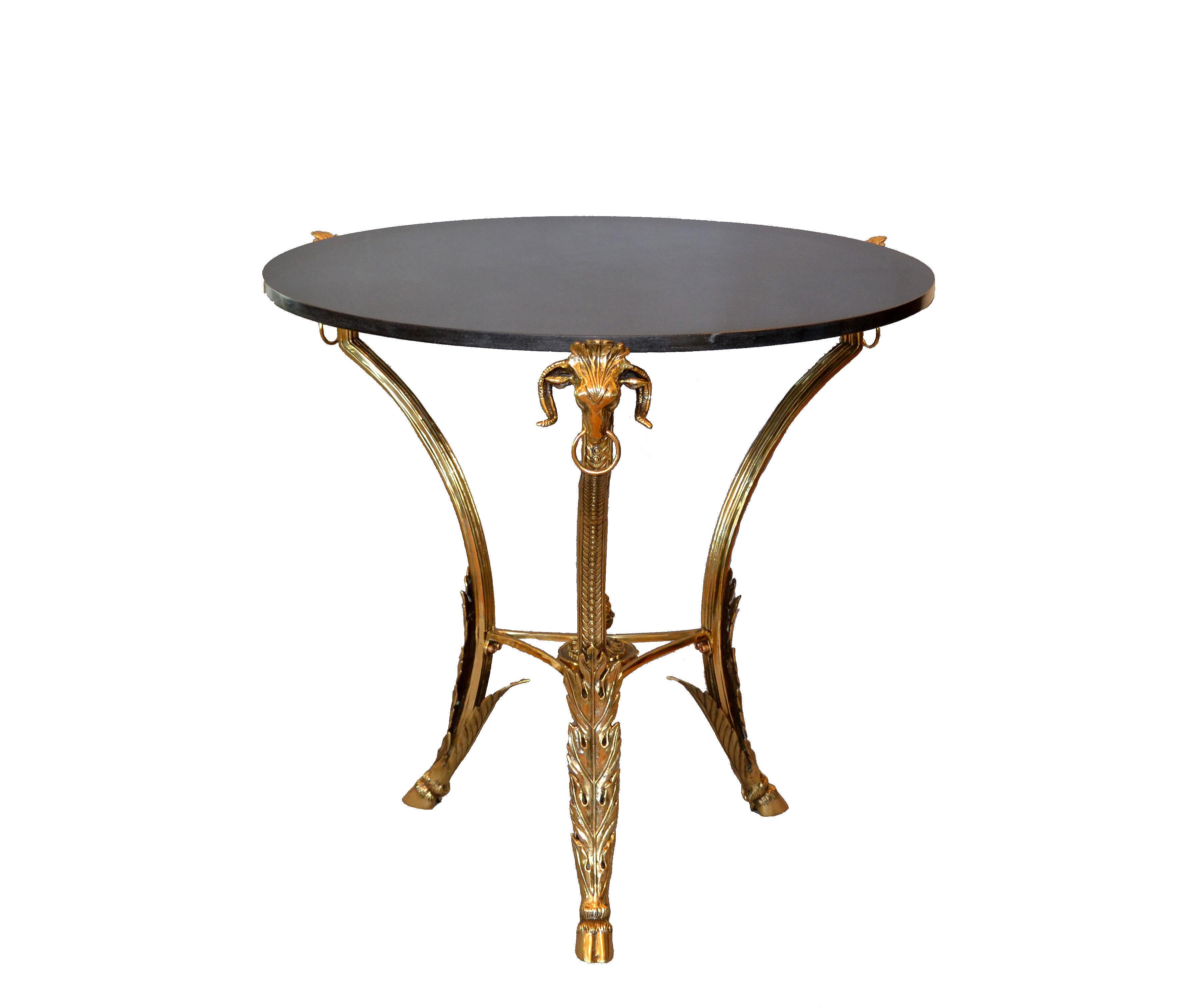 Cette table à café ou à cocktail ronde en bronze français de style Guéridon est dotée d'un lourd plateau en granit de couleur gris foncé.
Cette table présente une variété de détails en bronze comme les têtes de béliers, les pieds griffes et les
