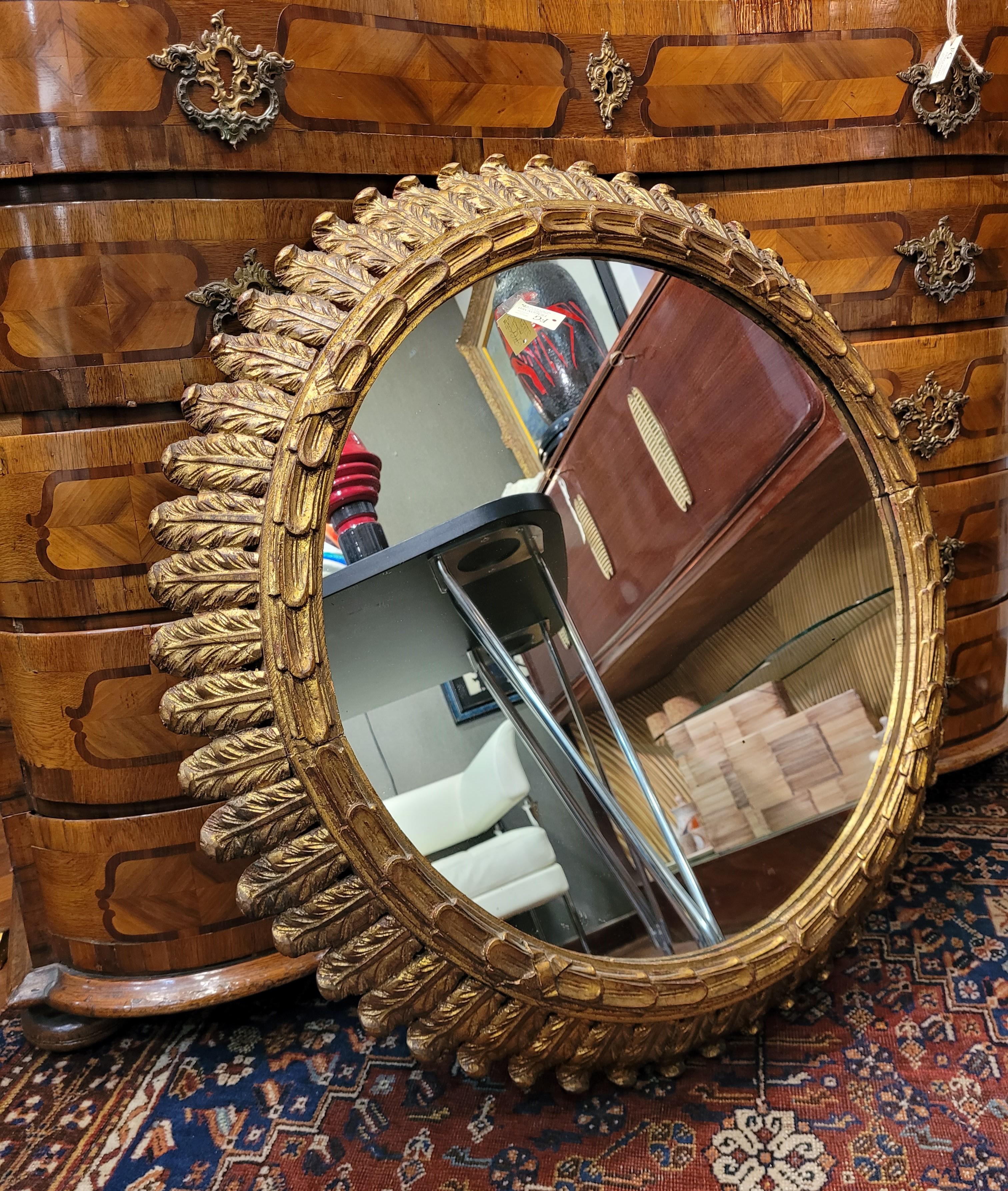 Gorgeous  mirror with a carved and gilded wooden frame, made at the beginning of the 20th century and of French origin. It comes from a private collection. The frame, with a circular profile, has two sections, the outer one is ornamented with olive