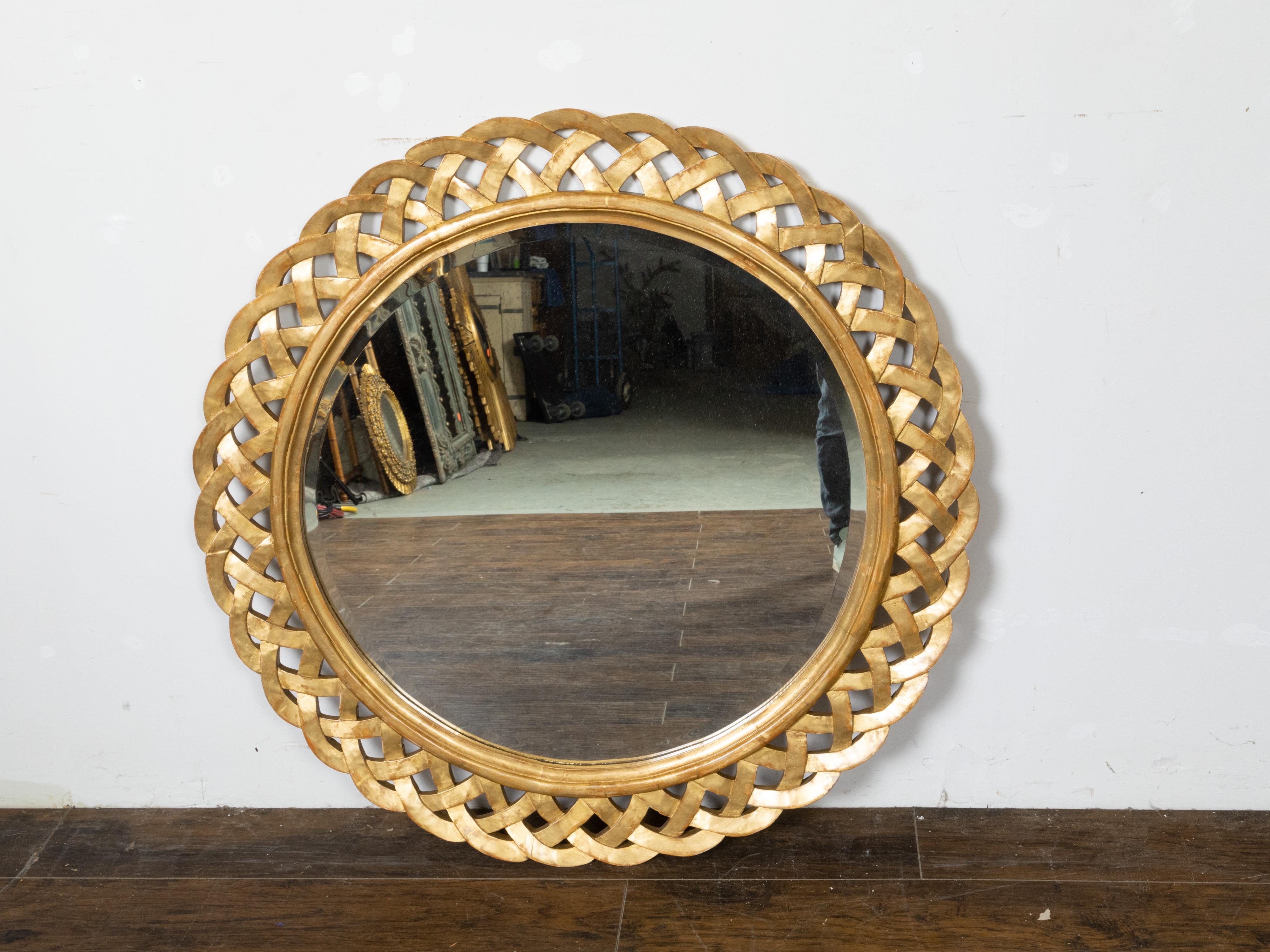 A French giltwood circular mirror from the 19th century, with woven trellis inspired frame and beveled mirror. Created in France during the 19th century, this giltwood piece features a round mirror plate with beveled accents, surrounded by a stylish