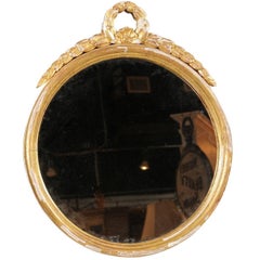 French Round Giltwood Mirror from the 19th Century with Swag Themed Crest