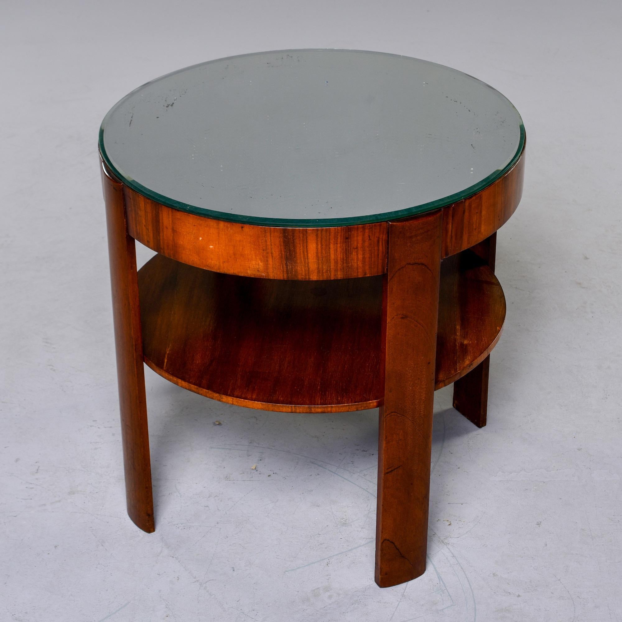 French two-tier round side table in flame mahogany with flat legs and mirrored top, circa late 1930s-early 1940s. Unknown maker.