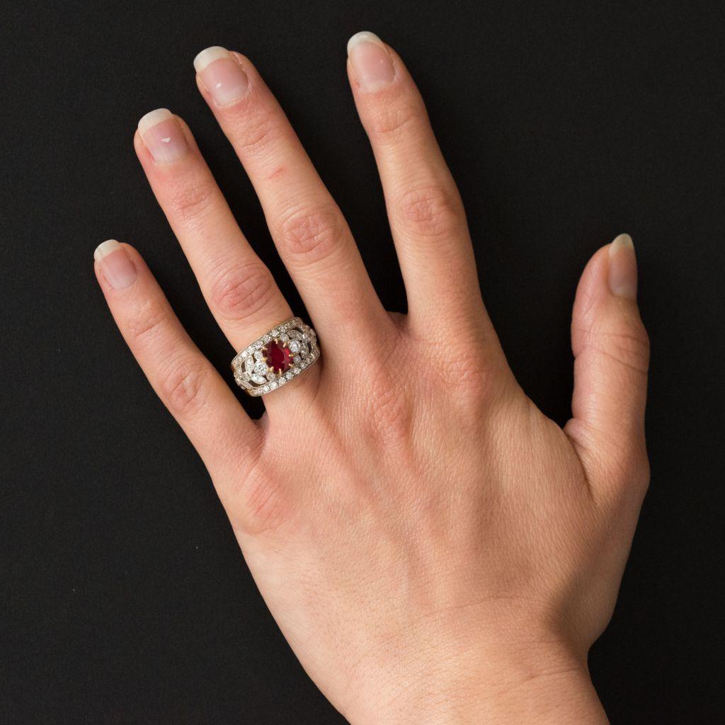 Ring in 18 karat yellow gold and platinum, dog and eagle heads hallmarks. 
This domed ring is decorated on its entire surface with an openwork floral design edged above and below with lines of diamonds.  At the centre is a claw set oval ruby. This