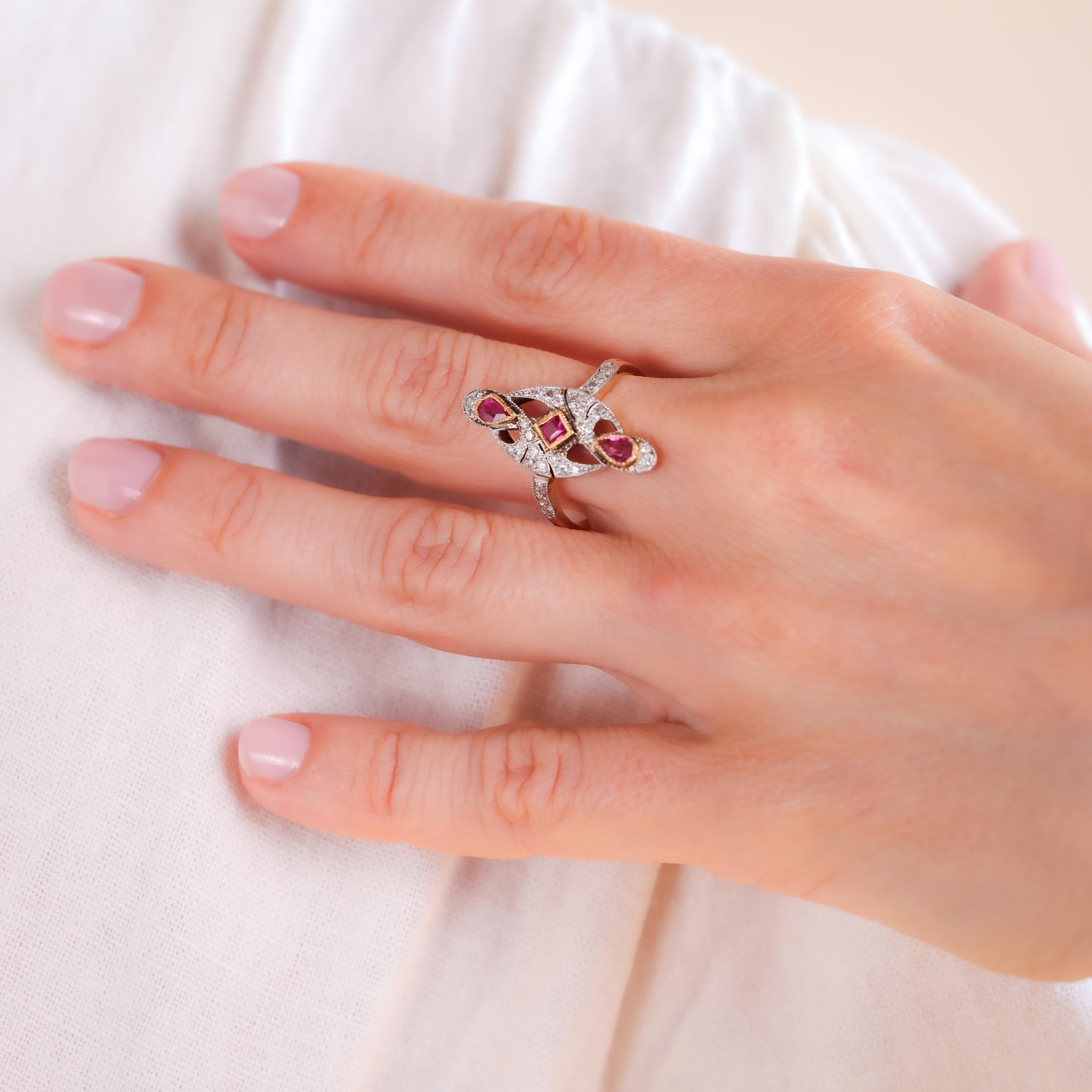 Center Stone: 3 Rubies
Cut: Pear and Asscher
Weight: Approximately 0.35 Carats
Color: Red
Accent Stone: 30 Diamonds
Cut: Round
Weight: Approximately 0.2 Carats
Color: F-G
Clarity: VS
Metal: 18K Yellow Gold and Platinum
Era: Retro
Style: Edwardian