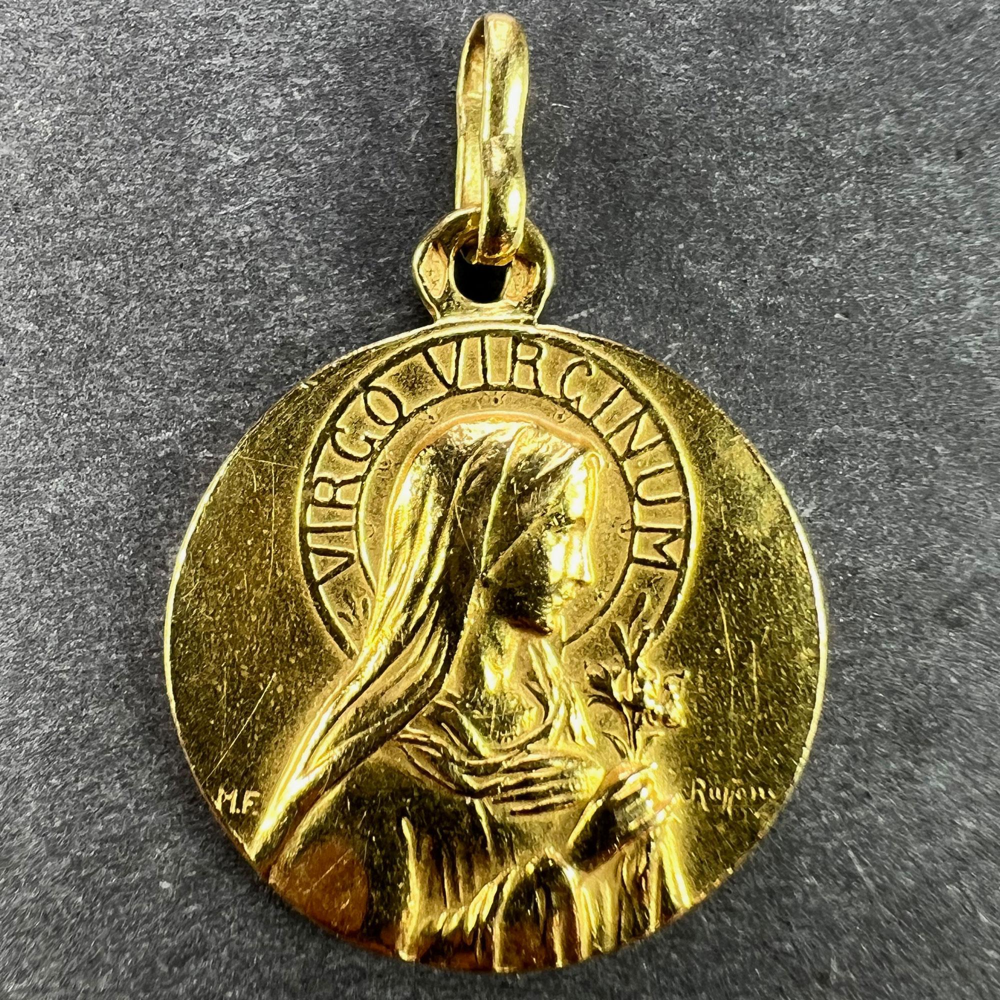 A French 18 karat (18K) yellow gold charm pendant designed as a round medal with a relief of the Virgin Mary in profile with a halo of the Latin motto 'VIRGO VIRGINUM' (Virgin of Virgins). The Virgin holds a sheaf of lilies to represent purity. The
